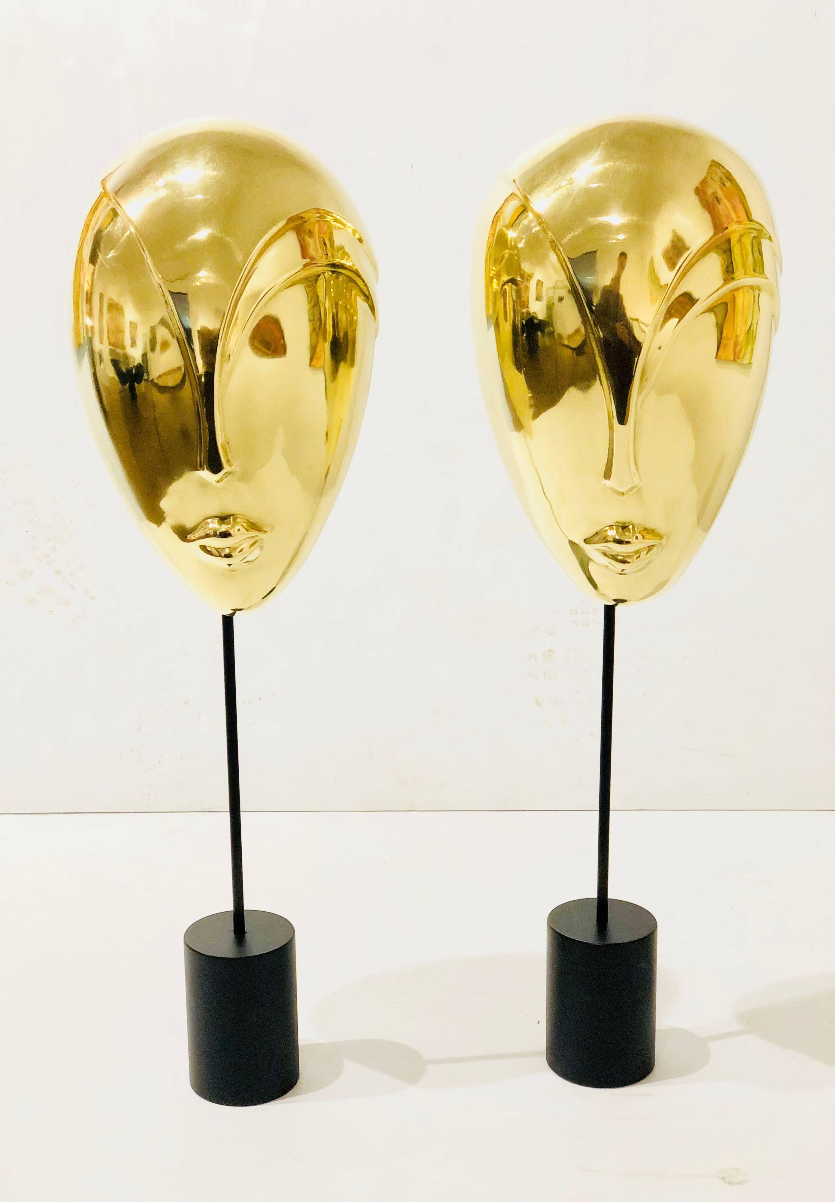 Unique pair of solid brass decorative masks sculptures in polished brass finish with black enamel finish bases.