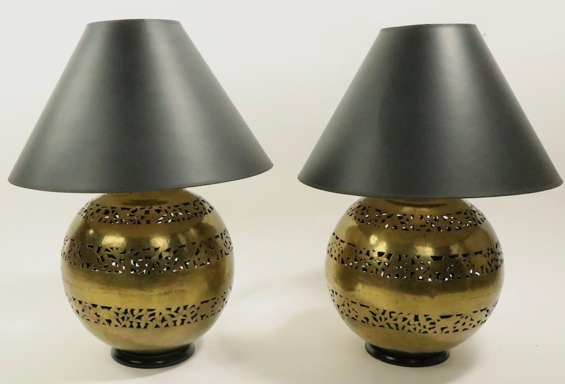 Wonderful pair of pierced brass ball form table lamps made min India, circa 1970s-1980s. The lamps have reticulated bands showing elephants and abstracted foliate as the decorative motif. Both lamps are in very good, clean, and working condition,