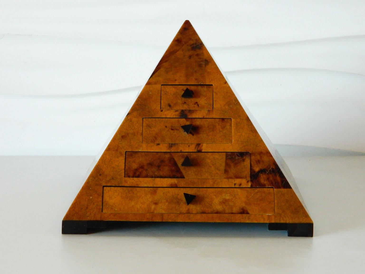 This pyramid-shaped decorative box in the style of Maitland Smith is made of burled wood that has been lacquered and sits upon a black base. It features four stair-stepped drawers lined with velvet and with triangular pulls.