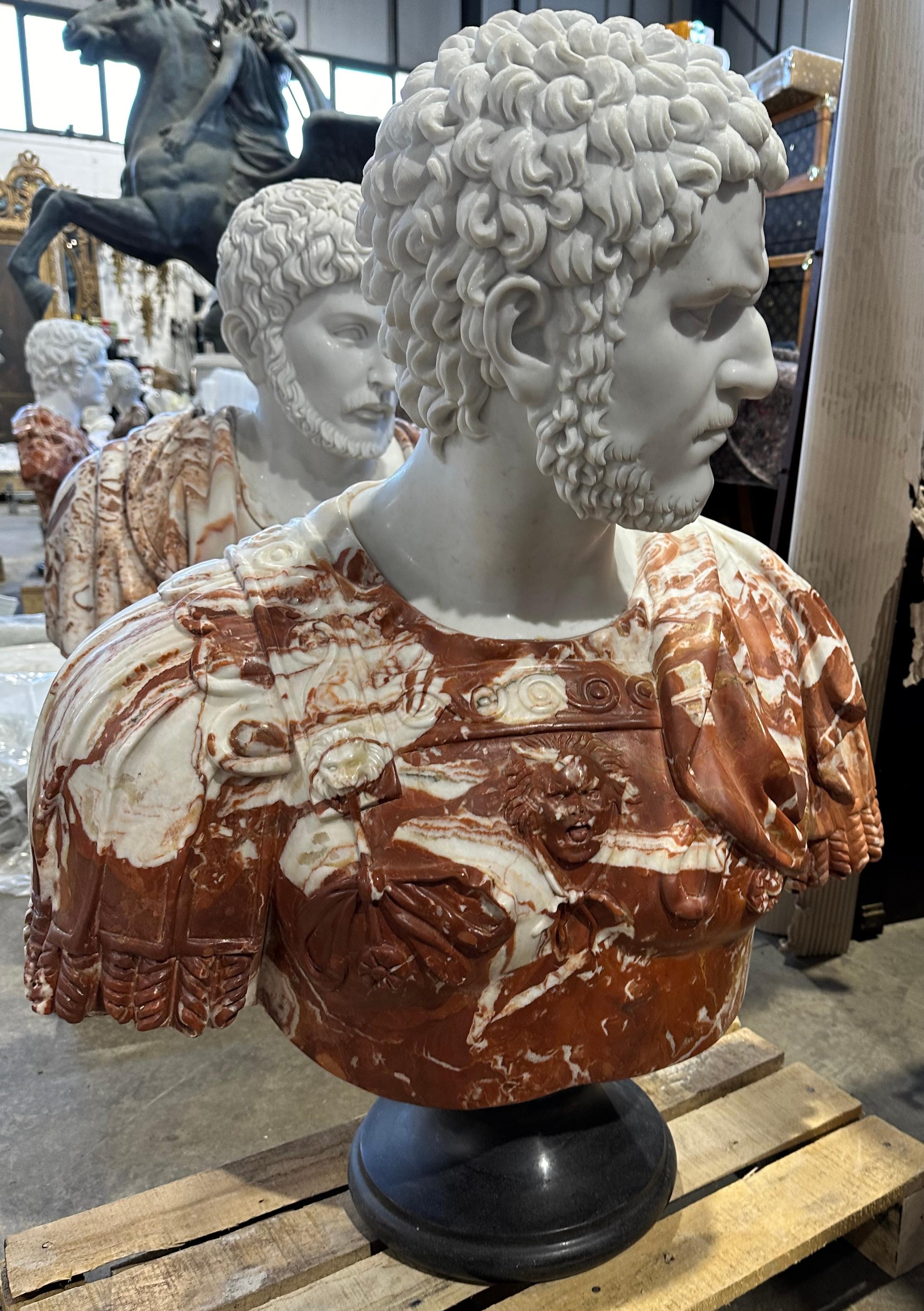 A highly decorative two coloured red and white marble Classical style bust on a black stand. Skilfully carved with clear features, curled hair and beard. The drapery of the garments hangs realistically and has lovely detailing to the edges. The