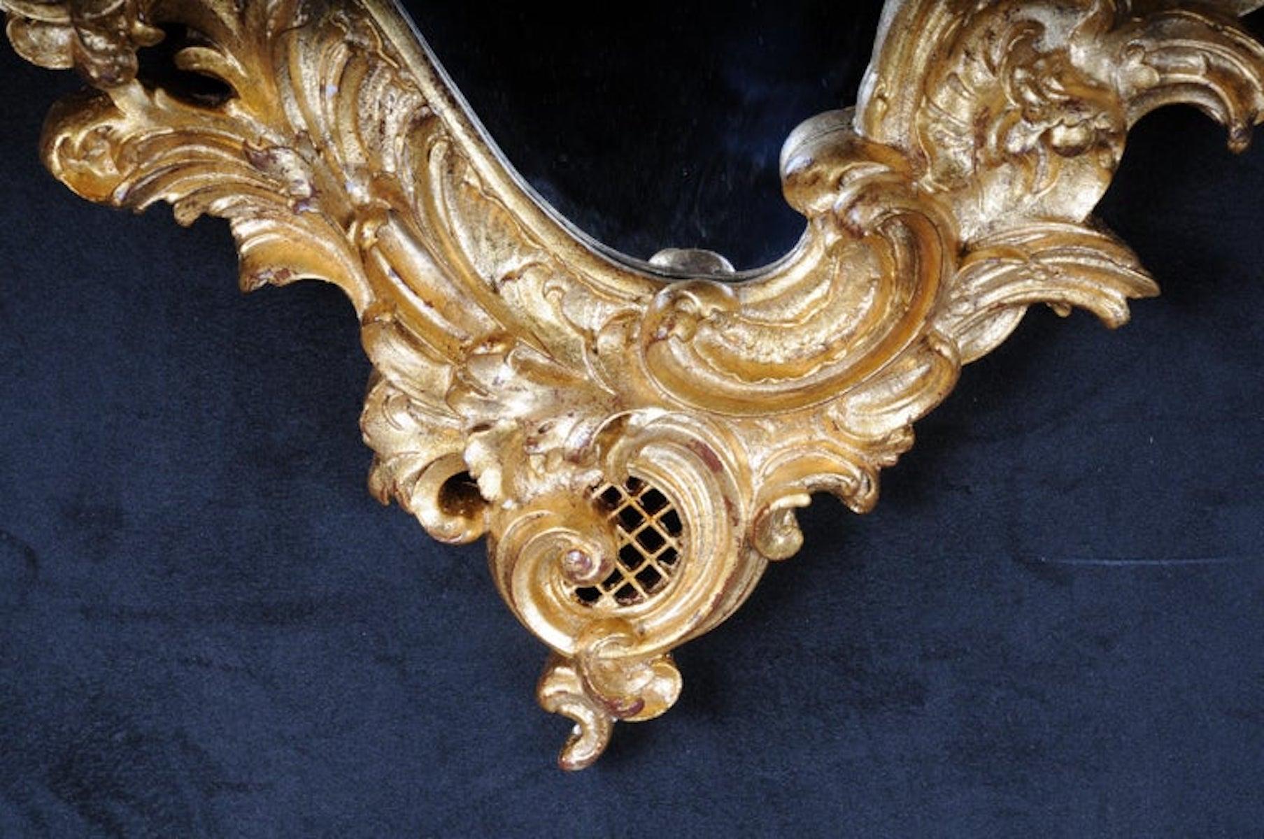 Decorative Rococo / Baroque wall mirror with putti, gilded

Solid beech, finely carved, gilded. Rocaille-shaped mirror frame. Openwork crown of rocaille. Extremely curly rocaille-shaped mirror frame. Crown of Rocaille.
