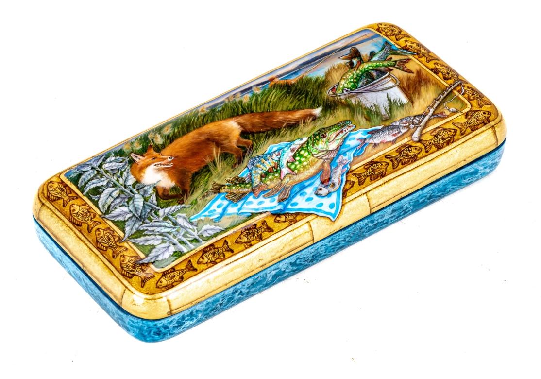 Caja decorativa rusa lacada a mano con bisagras e interior rojo. La caja con un zorro lamiéndose la boca al descubrir la captura de un pescador exhibida con orgullo. Un pescador inconsciente al fondo, más allá de las hierbas pantanosas, con la caña