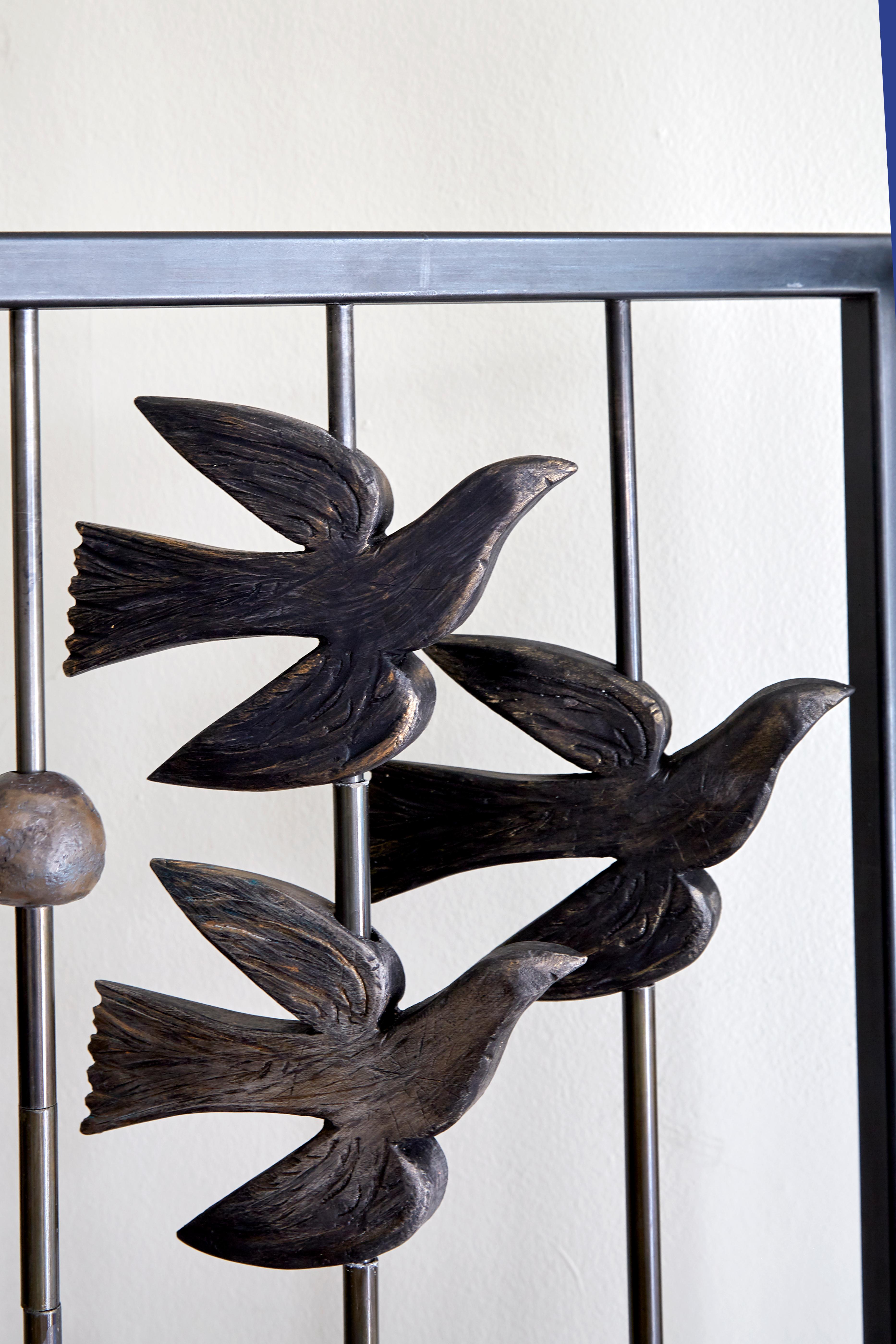 Le triptyque de Margit Wittig, écran en métal noirci et séparateur de pièce, présente des oiseaux sculptés en résine en vol. Ces pièces peuvent pivoter, ce qui permet au collectionneur de créer différents niveaux d'opacité et d'apparence du