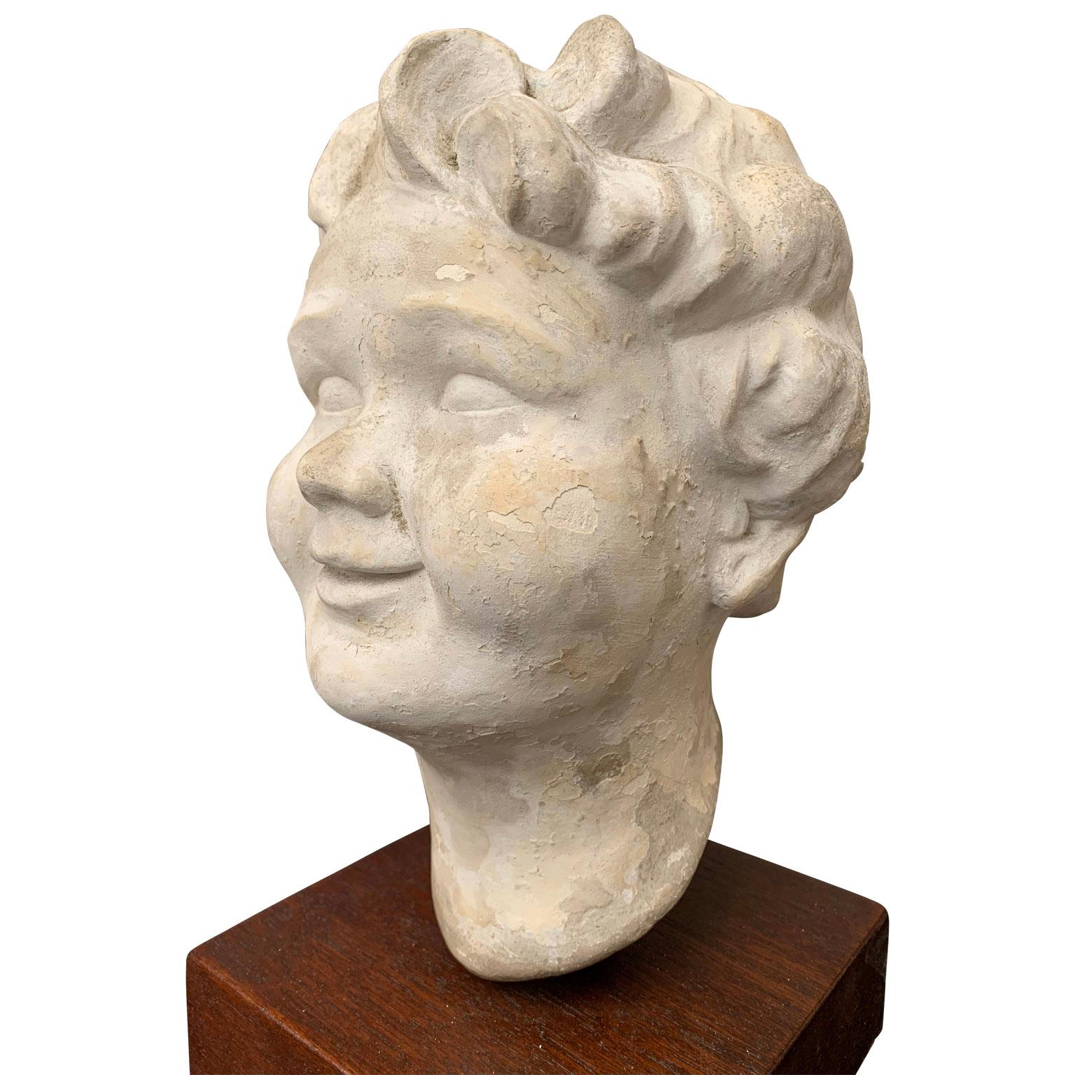 Plaster sculpture of putti's or Childs head on wooden stand

The sculpture is dated in the plaster with 