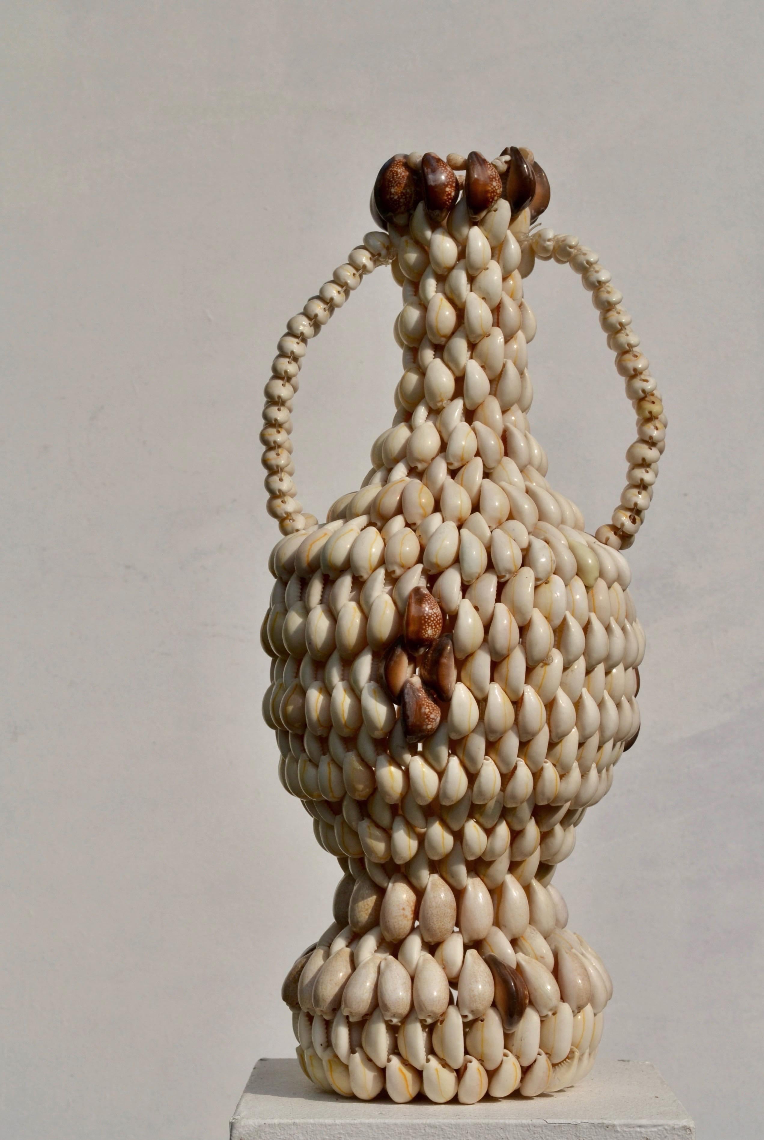 Diese Vase ist ein eindrucksvolles Beispiel französischer Handwerkskunst aus den 1970er Jahren. Sie besteht vollständig aus natürlichen Muscheln, die sorgfältig auf Draht aufgereiht sind und so eine skulpturale und dekorative Form bilden. Seine