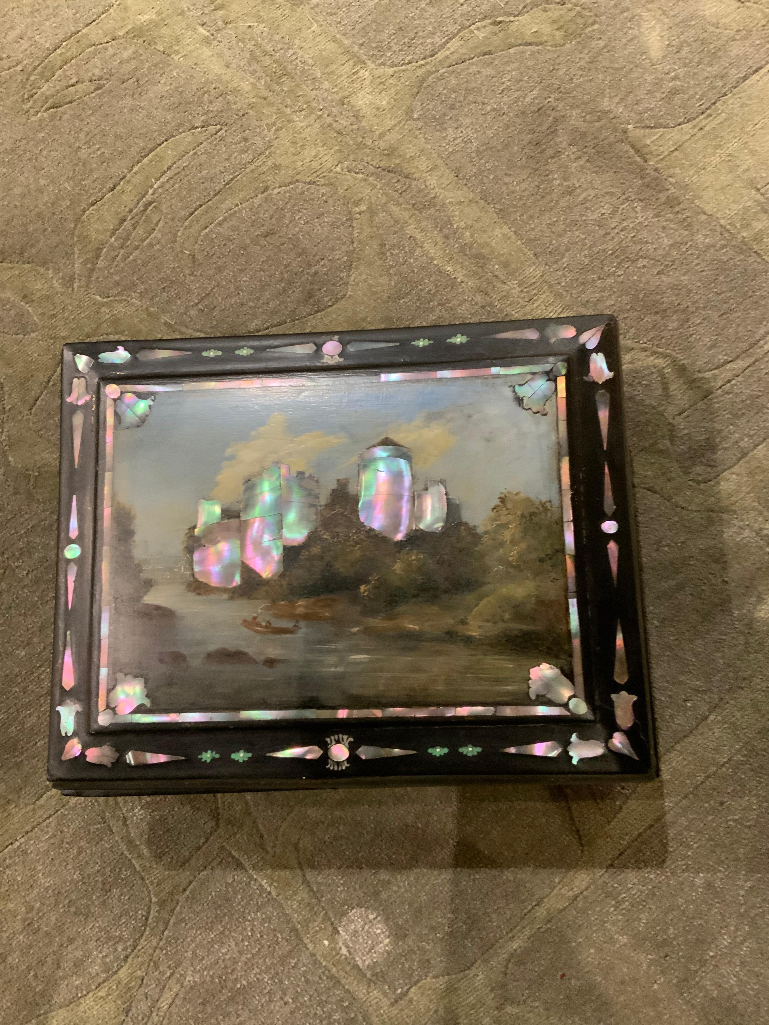This antique box is from London made from papier-mâché 
The top is hand painted and inlaid with mother of pearl.
It is finely painted and has an interior with defined
Spaces for writing implements and stationery the inside
Is lined with emerald