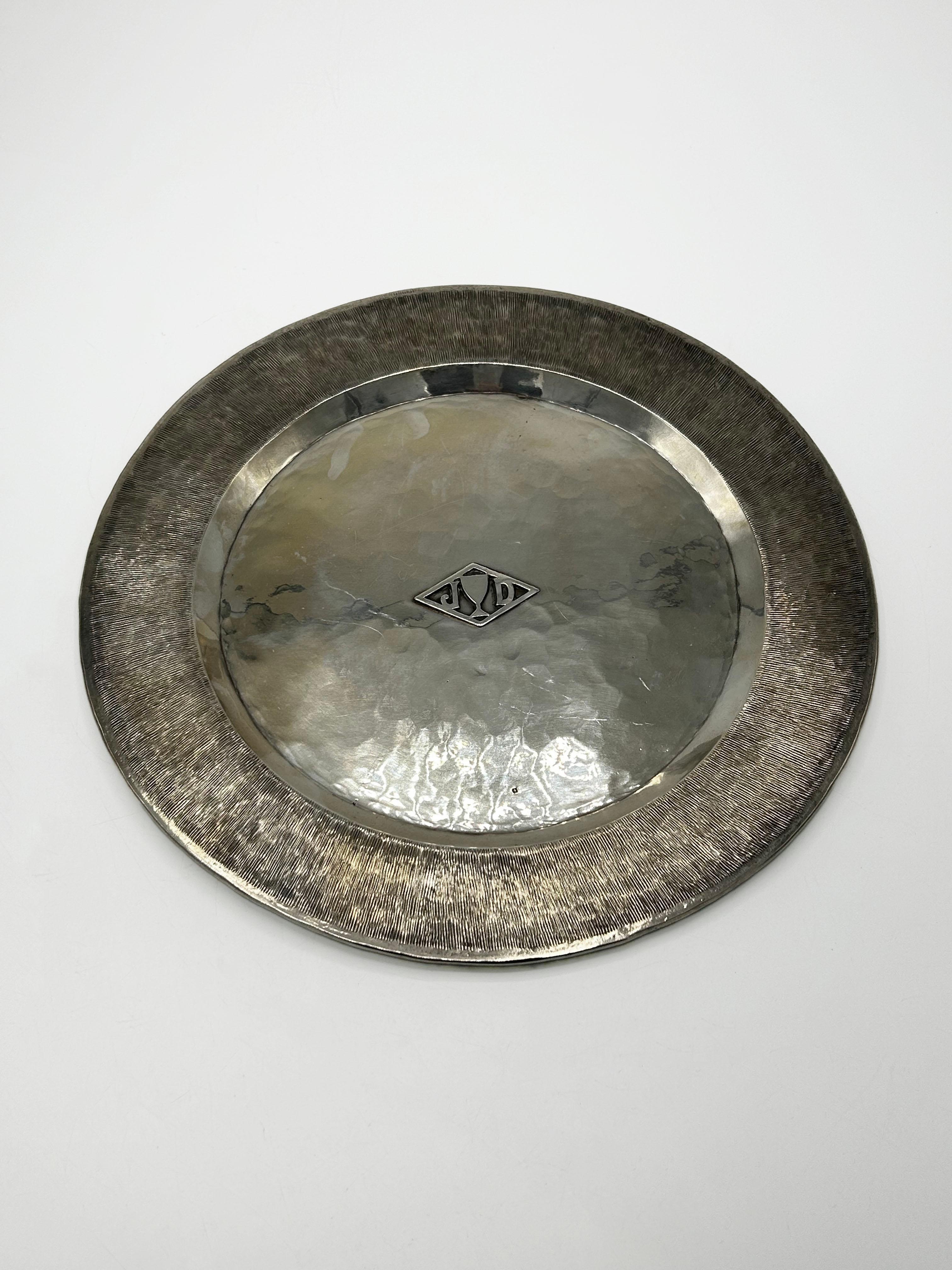 Silver-plated decorative plate by Jean Despres
This circular decorative plate or tray is made of silver-plated metal with a design combining contrasting textures, characteristic of the Art Deco style. The central field features a hand-hammered