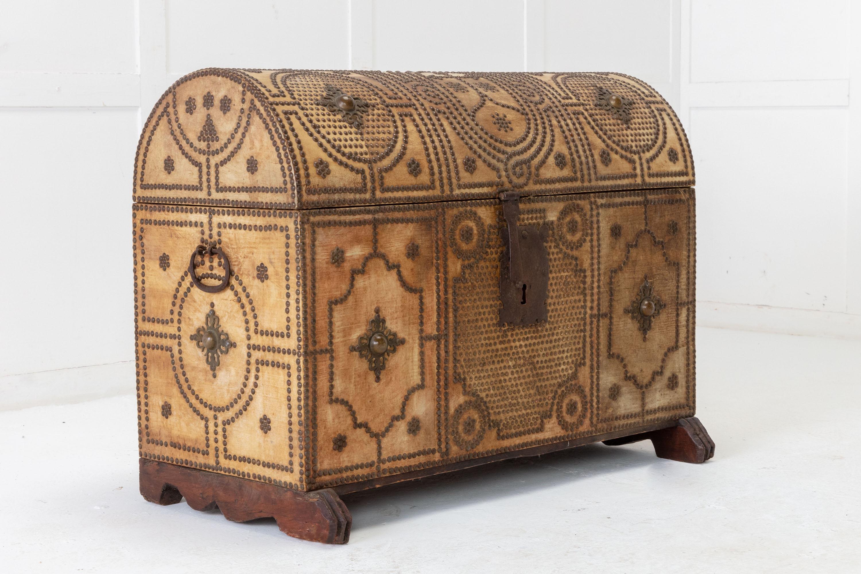 Decorative, Spanish travelling trunk with brass studded decoration. Having dome top lid and brass studded panels in geometric designs. The sides with original wrought iron carrying handles. The interior lined in old red linen and contrasting braid,