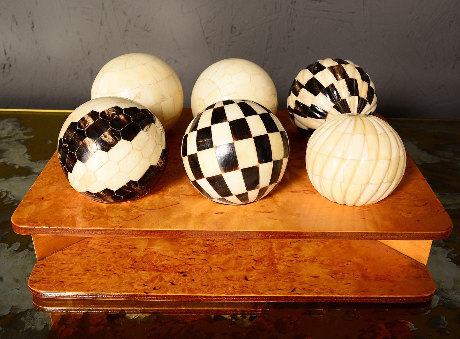 For your consideration a decorative set of six tessellated spheres, each with one design pattern. Made of ox bone and horn.

Custom display in burl wood tray. 

Unmarked, no information on the maker.
The tray measures 12
