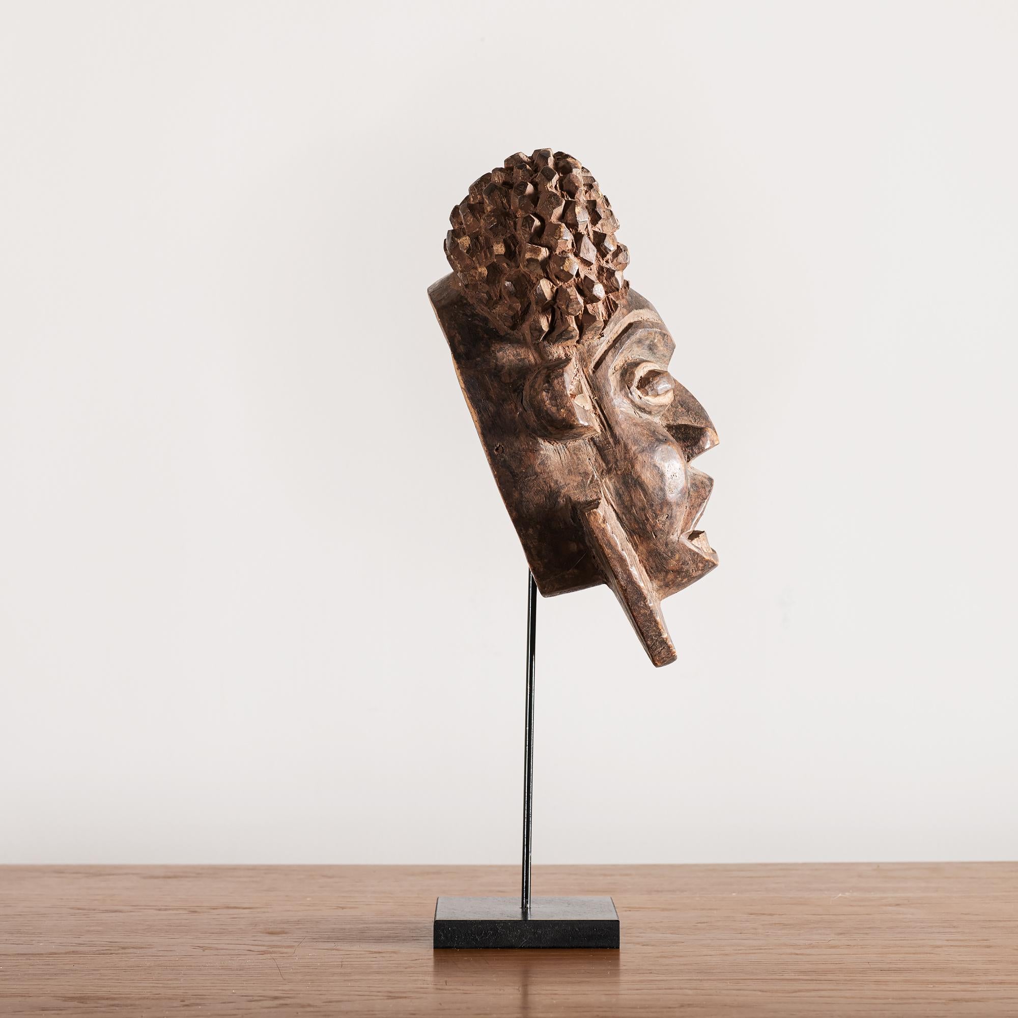 Bold and expressive decorative mask of carved wood from Cameroon, on pedestal base, 1950s. 

Measure: Height including base: 20 in.