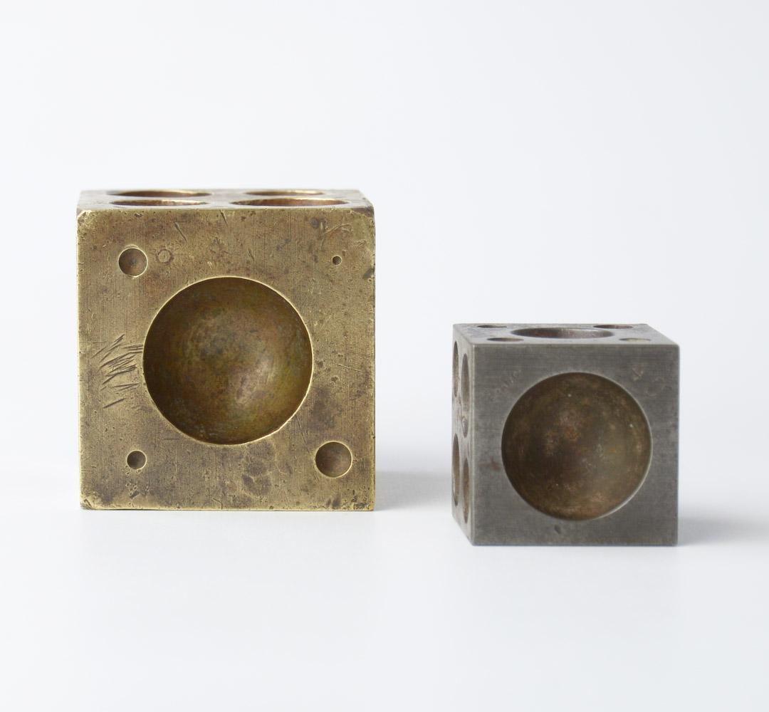 This pair of vintage cubes were originally used by a jewelry maker. The big one is made of brass, the other is made of metal.
They are decorative objects that can be used as paperweights.
Both cubes are in good condition, with a nice patina.