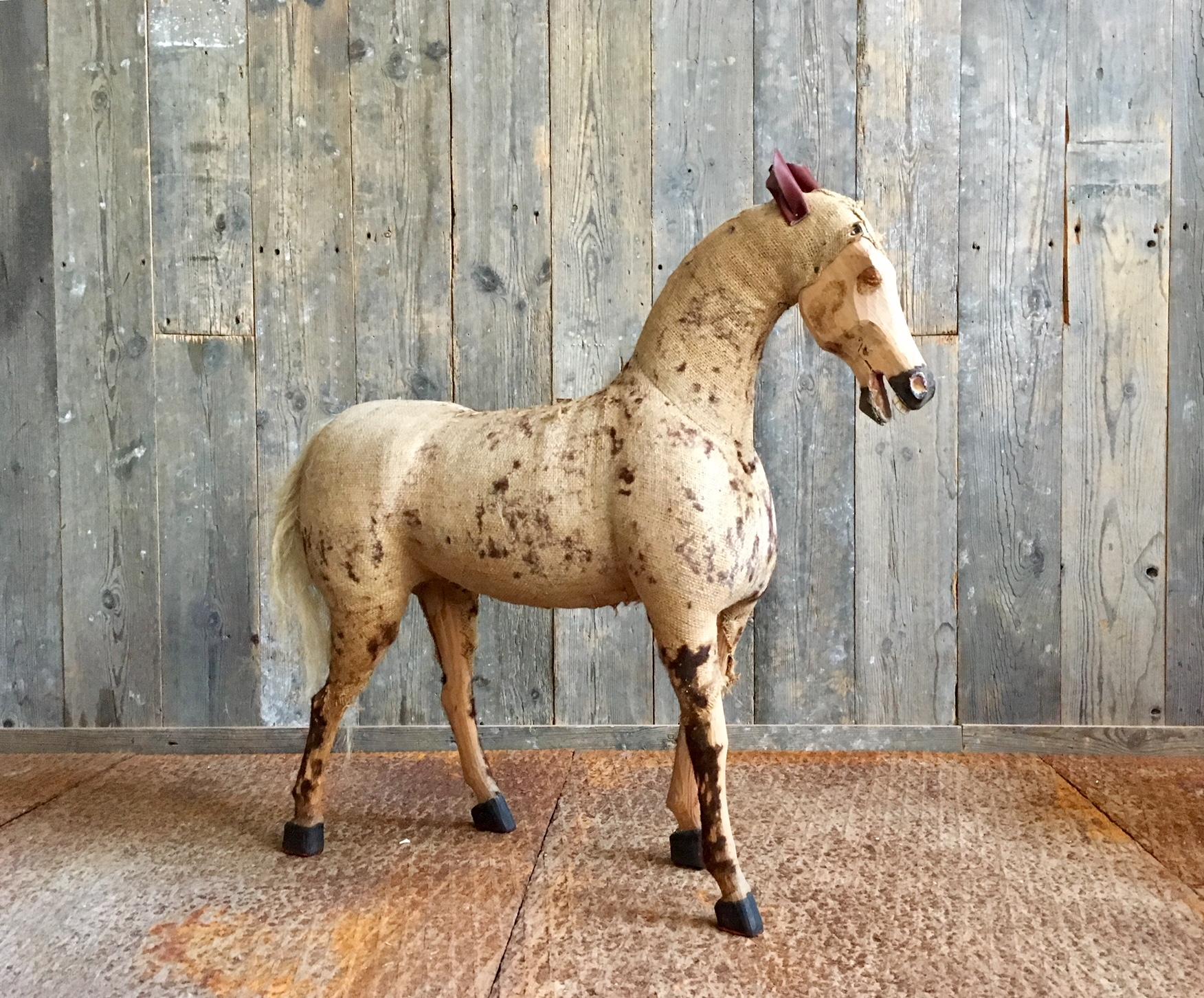 Decorative vintage horse in worn burlap, leather and wood. This horse used to be covered in a fur fabric but only parts of this fabric remain. What's left gives the horse a beautiful vintage, worn and weathered look. 

The horse is 84 cm in height