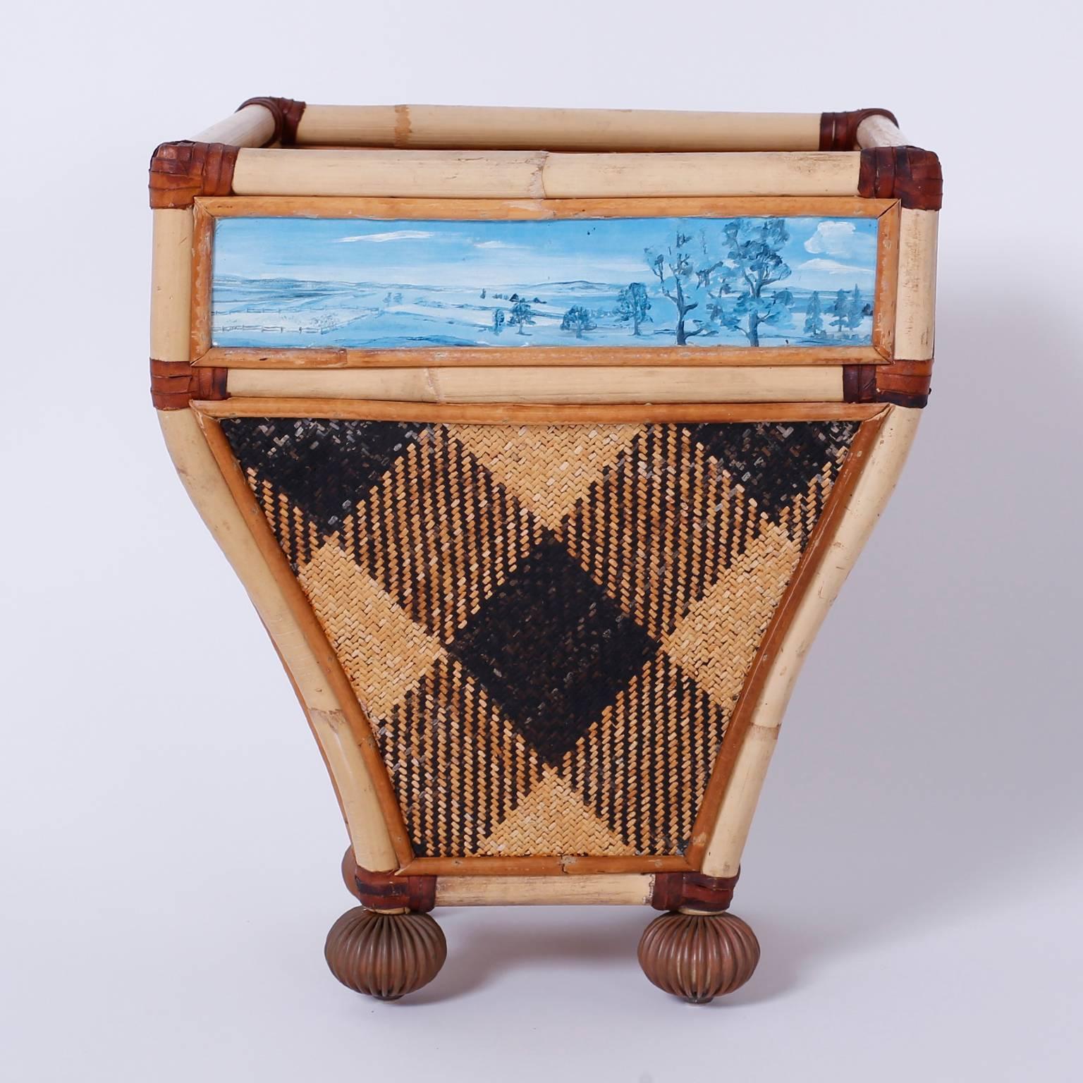 Well-dressed waste basket crafted with bamboo, wicker and
reed. Featuring four monochrome landscapes with woven argyle side panels and beaded bun feet.