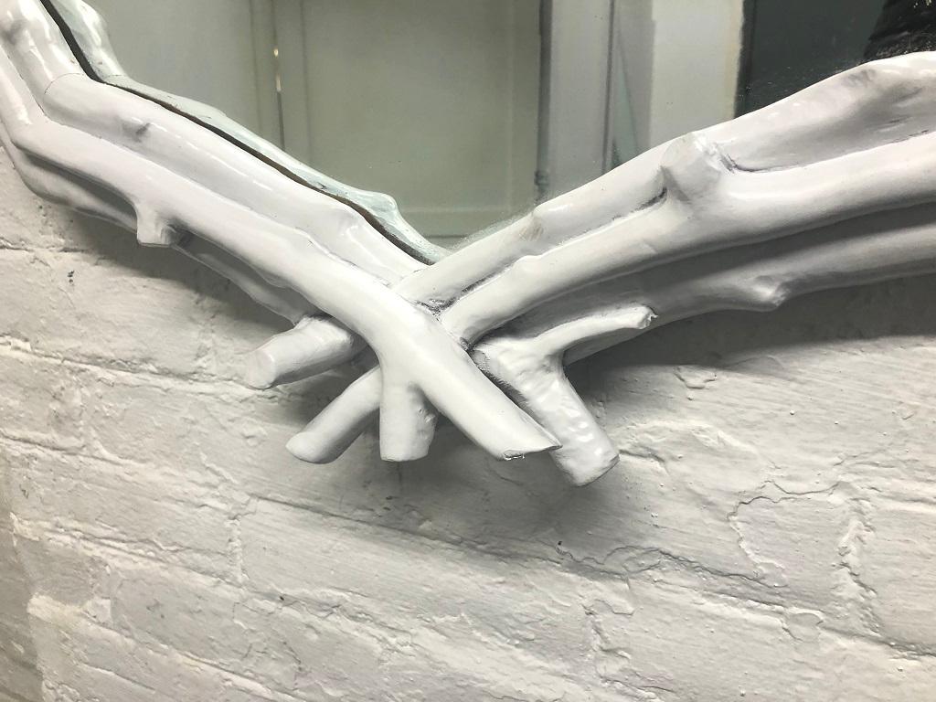 Decorative white twig mirror. The frame of the mirror is hardwood and the twigs are made of a resin material with a white lacquered finish.