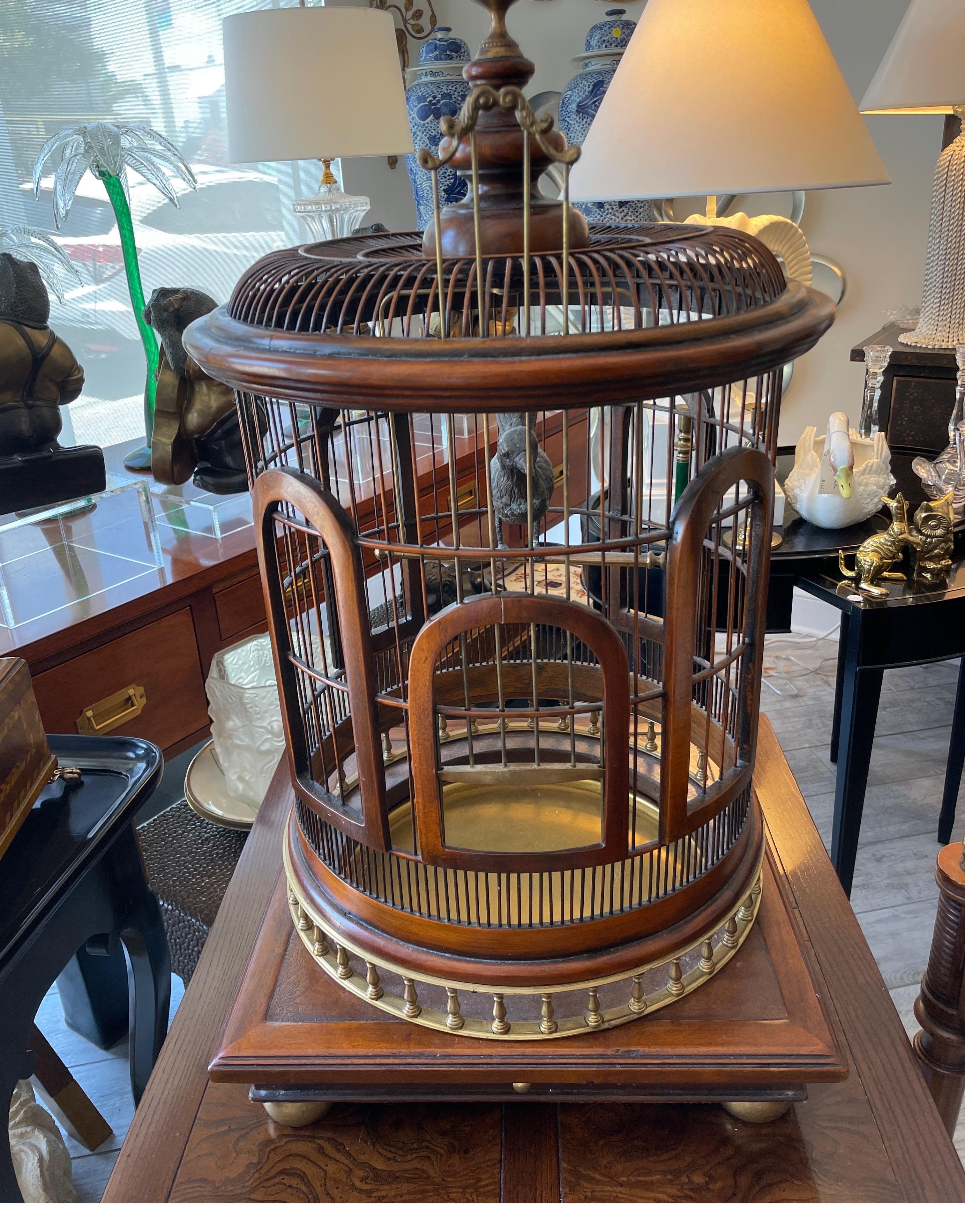 Vintage wood and brass bird cage. This cage is functional. The door raises up & down. The bottom brass tray pulls out for cleaning. It comes with a brass bird on a perch in the center. The outside is topped with a large brass acorn. A very striking