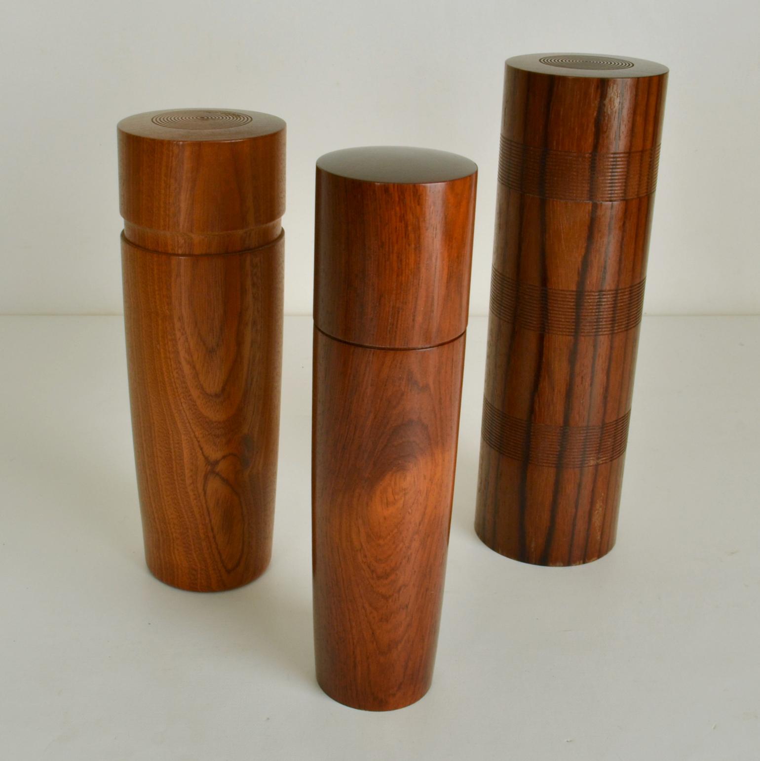 Conjunto de cinco refinadas cajas de madera torneada a mano, cada una de ellas con un ejemplar diferente de madera, en forma de cilindro recto y cónico de varias alturas, que muestran un excelente trabajo artesanal. Las vetas y los patrones de la