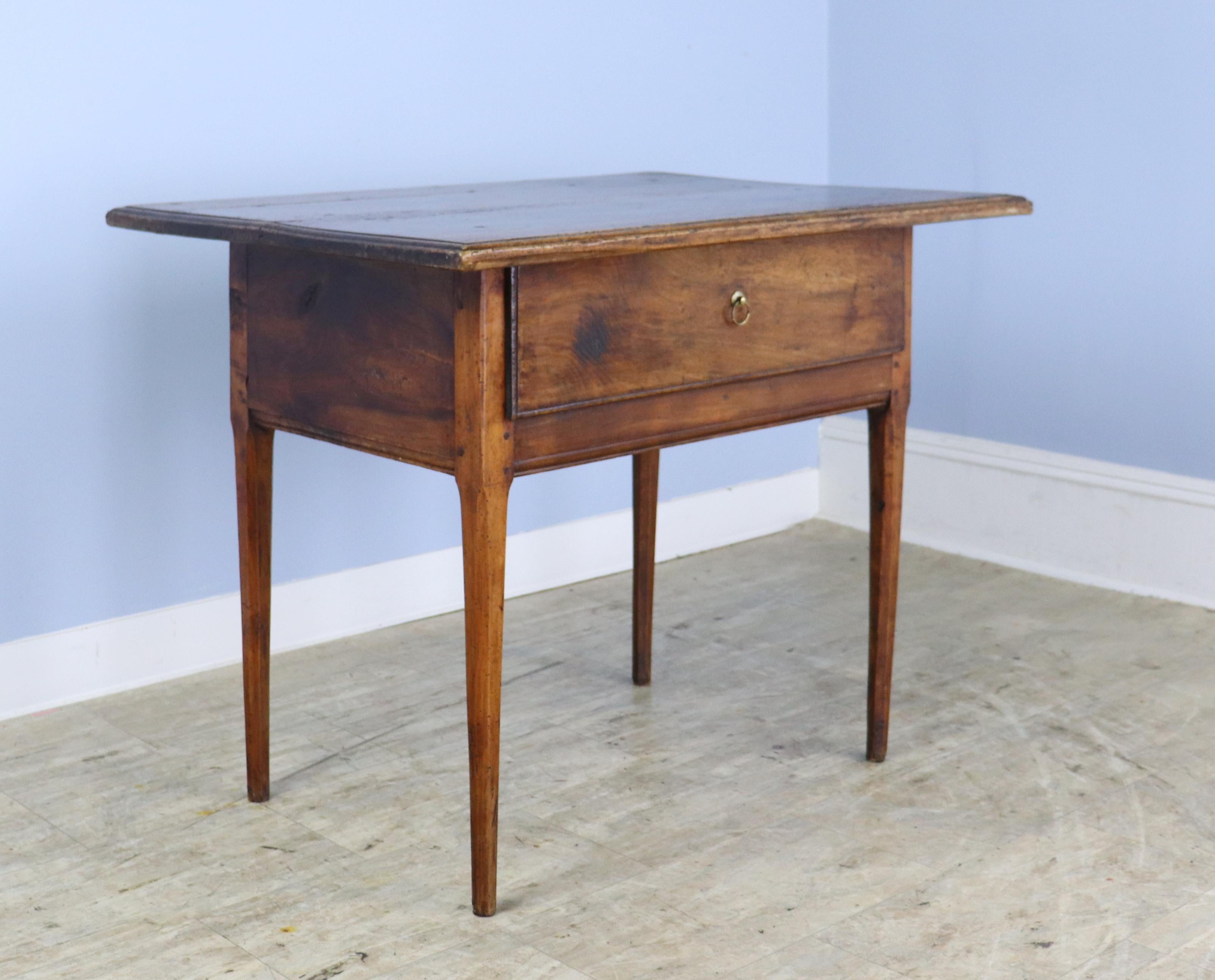 A generously proportioned walnut side table with a single very deep drawer.  Good moulded edges on the top and interesting age appropriate wear.  Slightly fluted legs.  Wonderful patina and color.