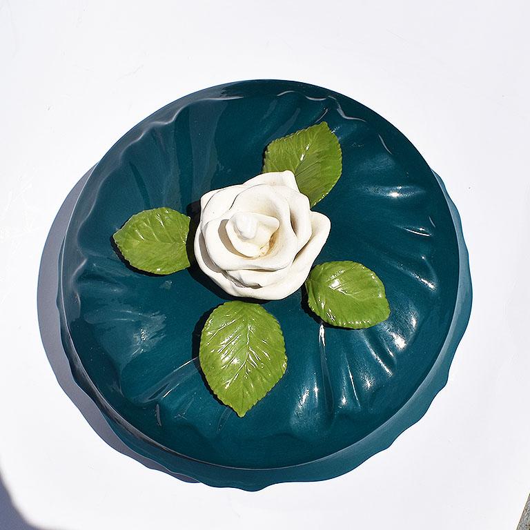Deep blue ceramic dish with matching lid. This beauty features a pretty white ceramic Magnolia flower with green leaves at the top of the lid.

Measures: 4.25