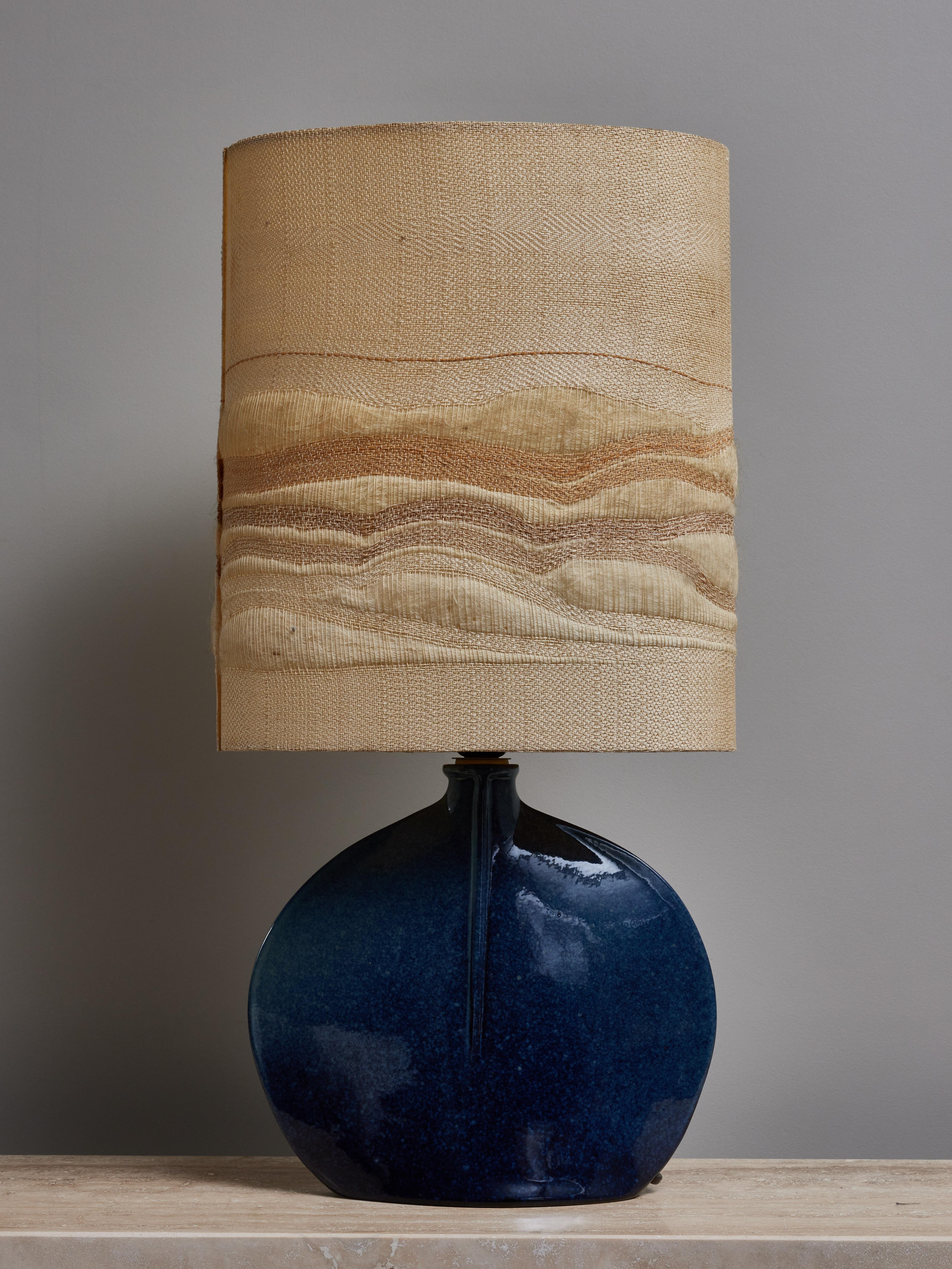 Elegante petite lampe de table en céramique émaillée, surmontée de l'abat-jour tissé d'origine.
