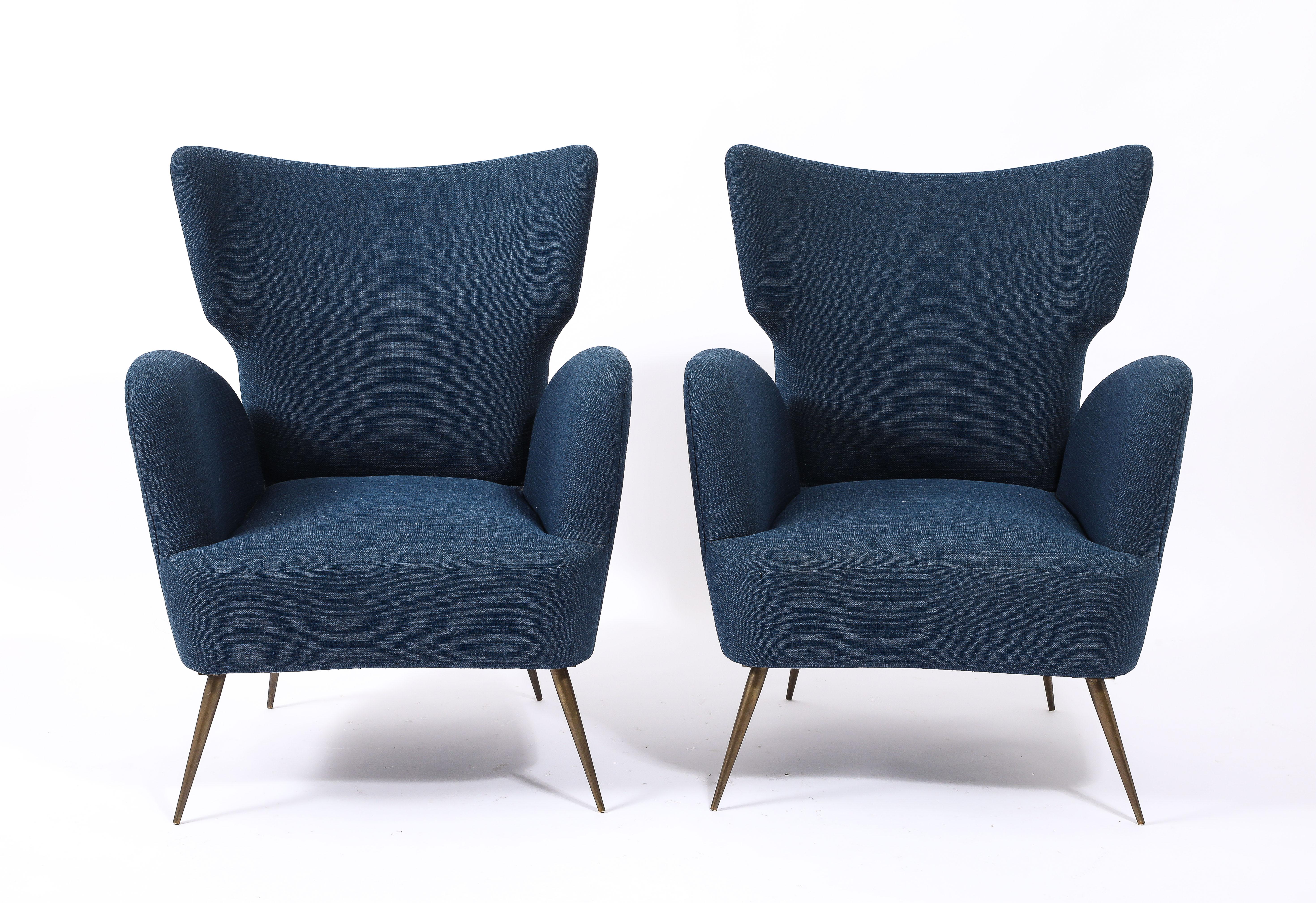 Dynamic wingback armchairs reminiscent of Minoletti and Buffa. Upholstered in a blue Linen, on brass legs.
