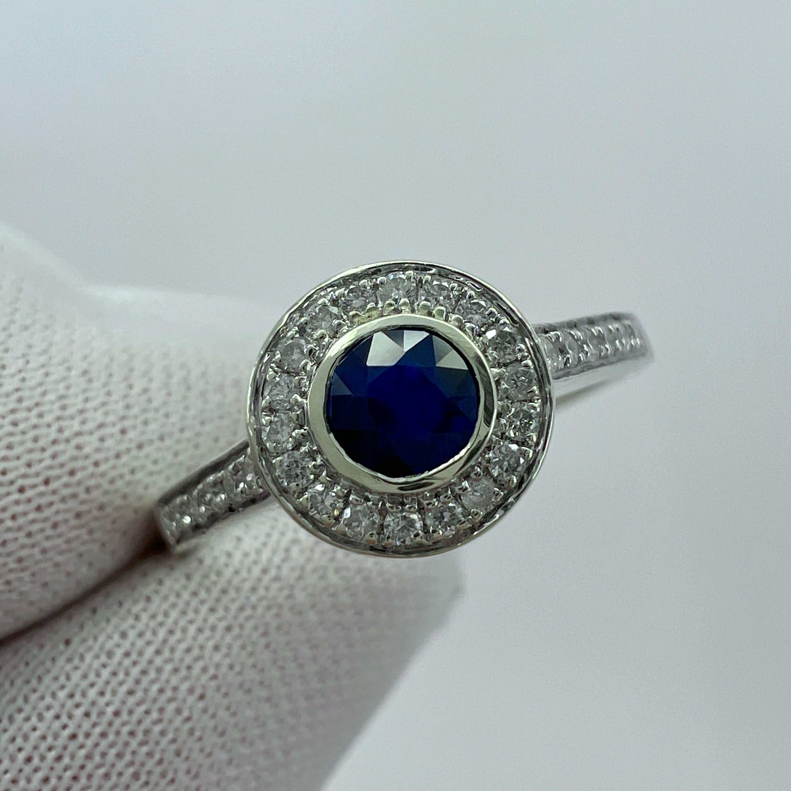 Natural Deep Blue Round Cut Sapphire And Diamond White Gold Halo Ring.

0.54 Carat total. This ring features a beautiful natural blue sapphire centre stone with a deep blue colour and very good cut and clarity. The sapphire measures 4mm (0.40