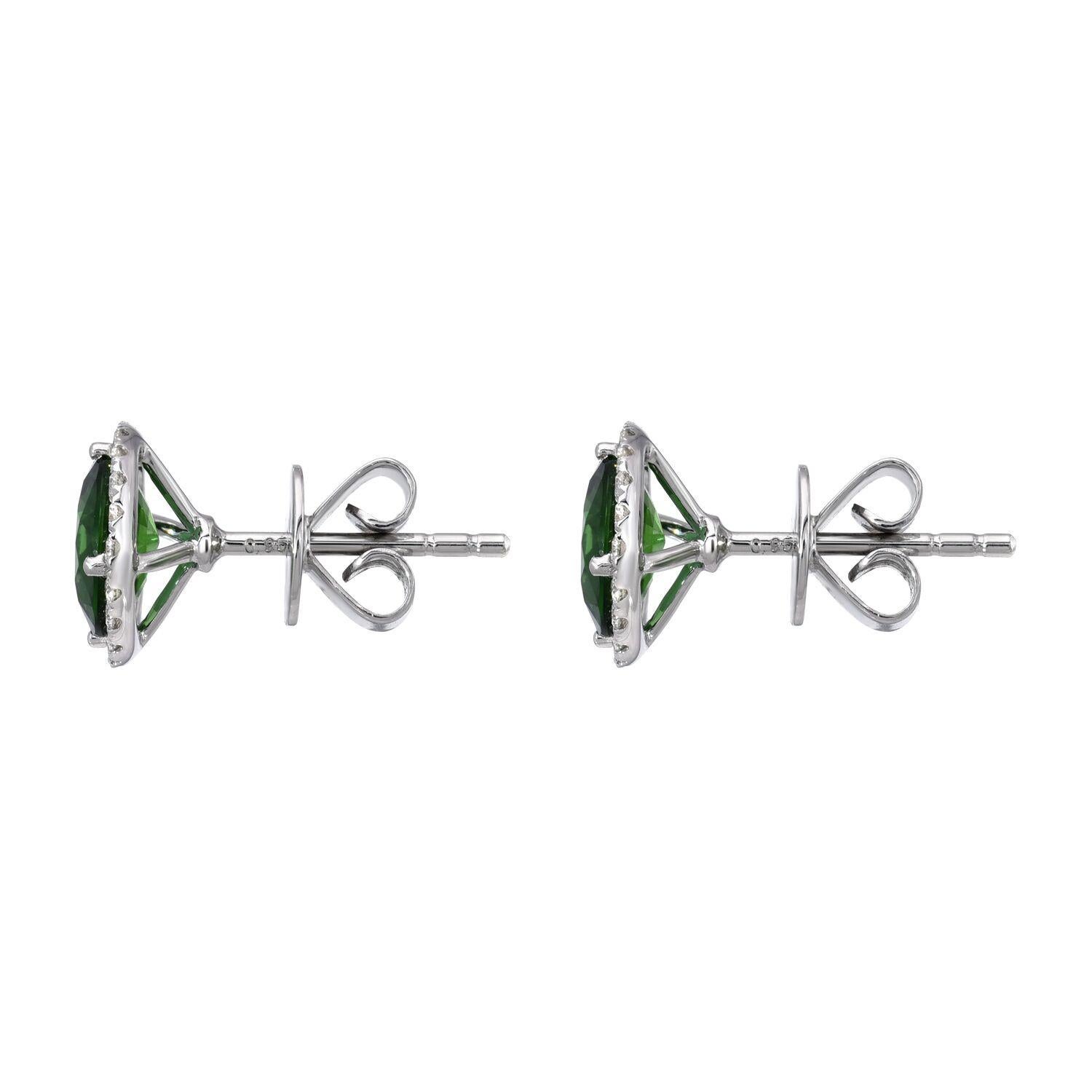 A pair of deep Chrome Green Tourmaline rounds, weighing a total of 
1.96 carats, are surrounded by a a halo of round brilliant diamonds weighing a total of 0.25 carats, in these 18K white gold stud earrings for women.
Returns are accepted and paid