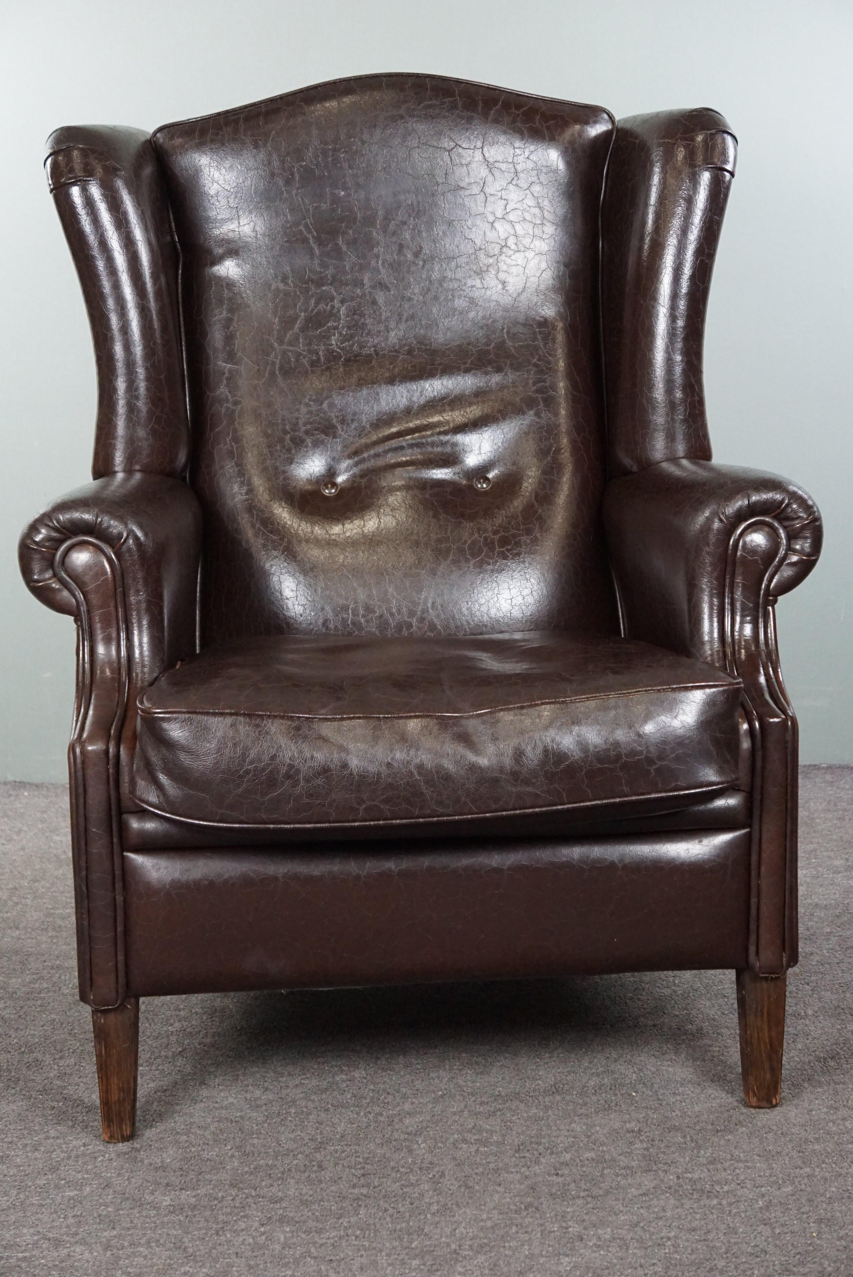 Nous vous proposons ce fauteuil à oreilles en cuir bien ajusté, d'une belle couleur brun foncé. Ce fauteuil à oreilles en cuir brun foncé, extrêmement bien conservé et impressionnant, rehausse votre intérieur. Ce fauteuil incarne non seulement une
