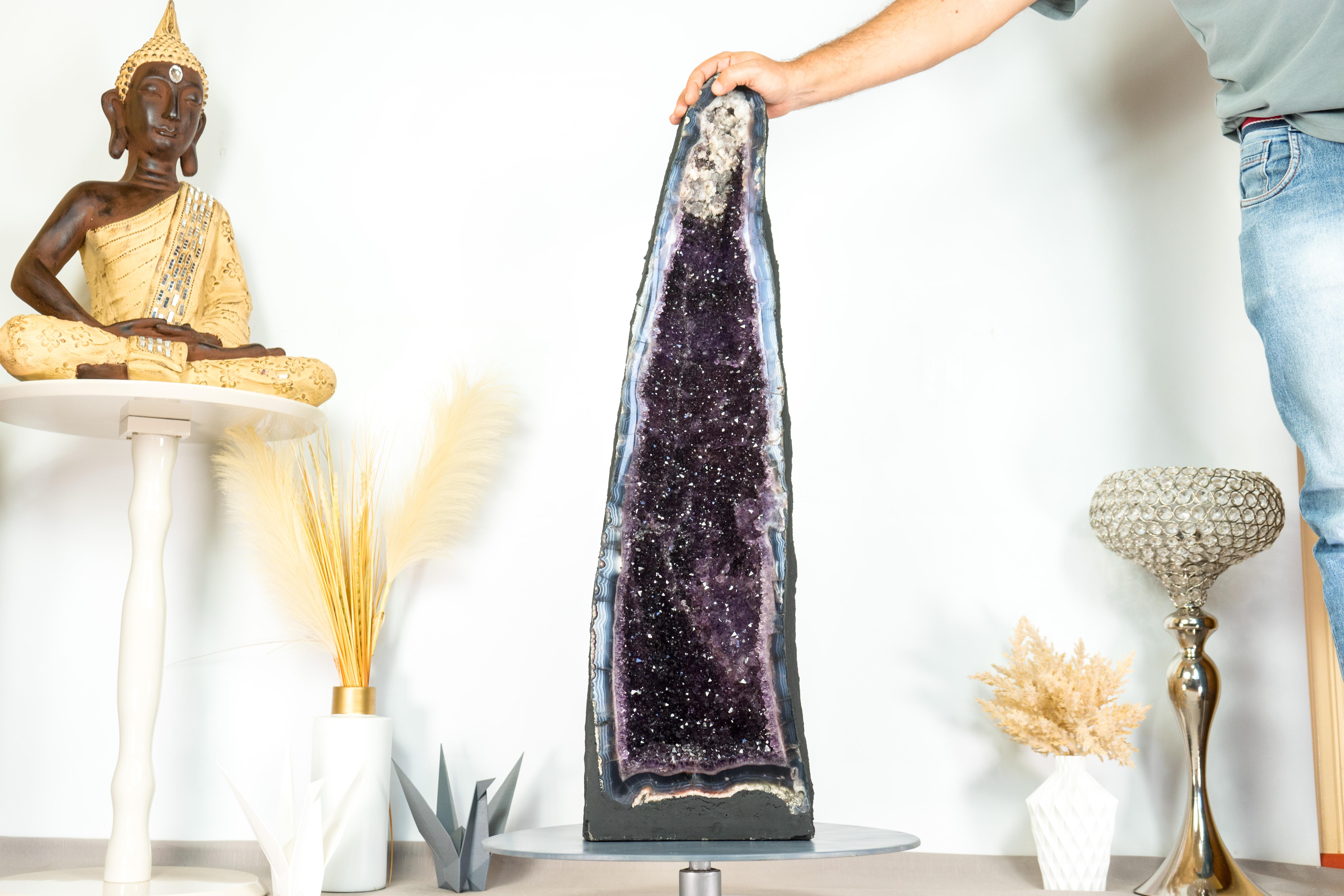 Breathtaking and beautiful, this Agate with Amethyst Geode features spectacular blue-banded agate lines and rare, stunning aesthetics. Enhanced by shiny Amethyst that perfectly complements its beauty, this all-natural artwork is destined to be the