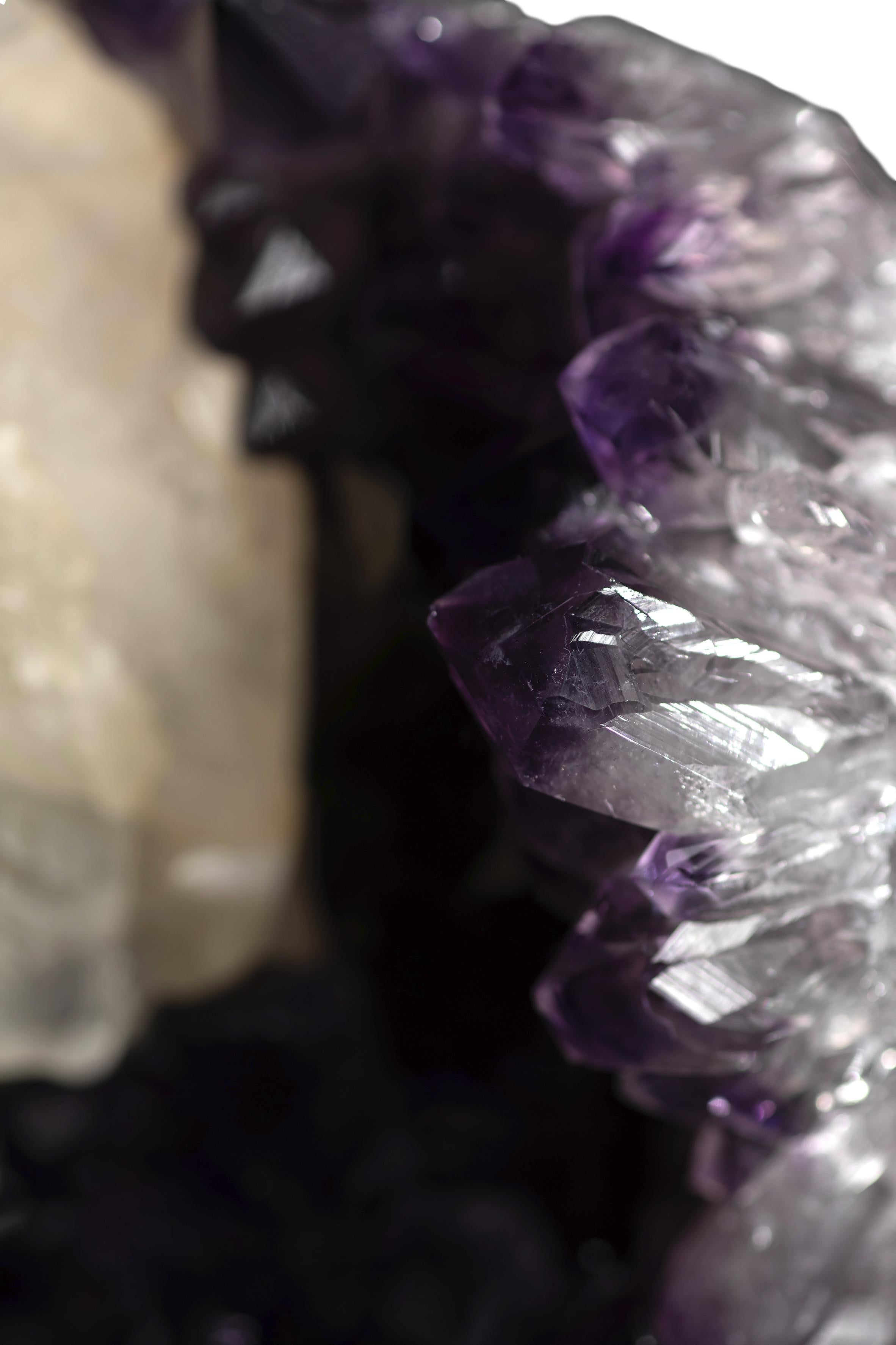 A exquisite amethyst geode cluster with an incredible calcite formation at the top. The interior of the piece is contains a very deep cavity which presents very high-quality amethyst, due to its deep purple high peaked crystals with a rare calcite