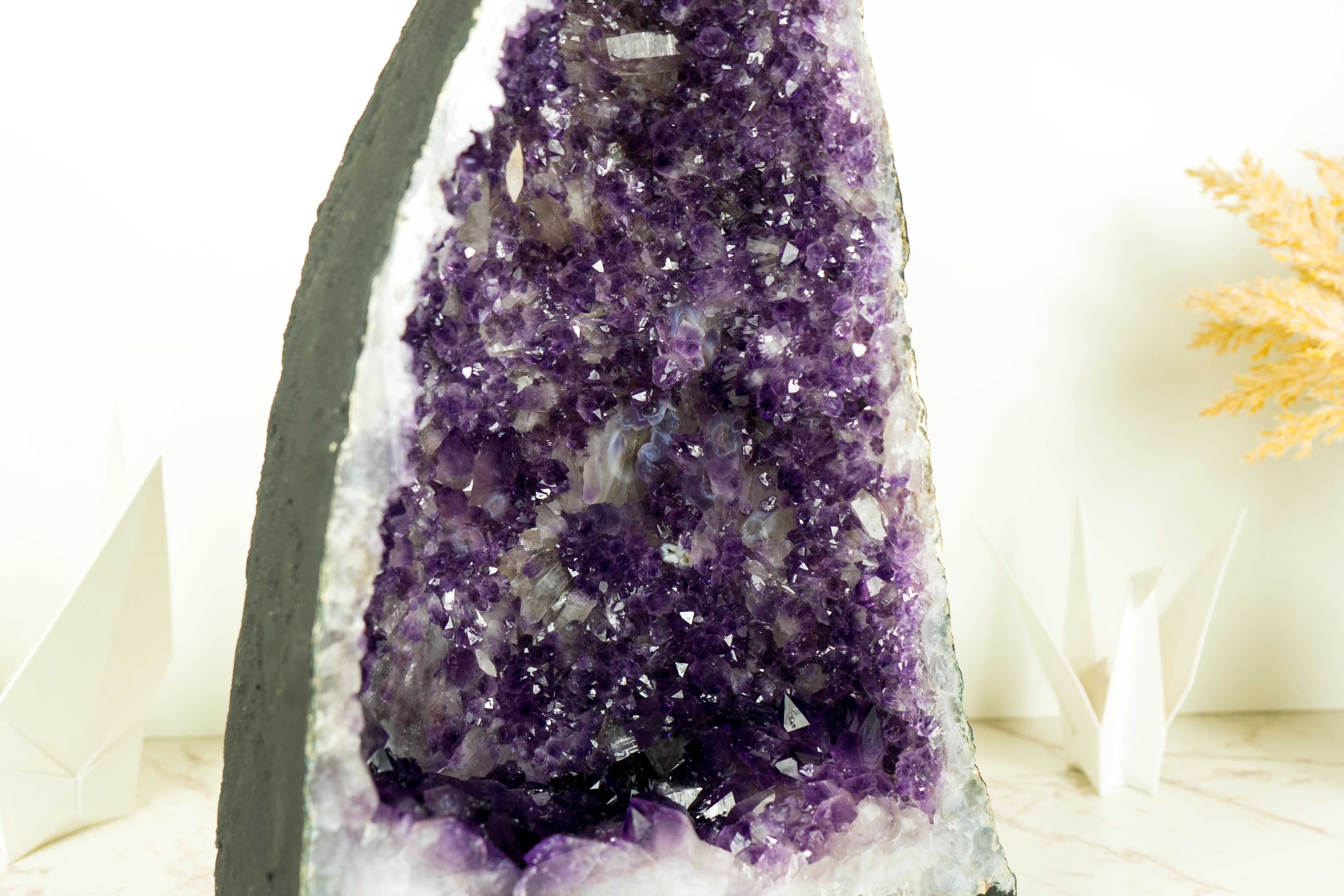 An Amethyst Geode that brings rarely seen dual-zoned purple Amethyst druzy, gorgeous aesthetics, and rare double-terminated calcite inclusions, this is a piece of natural artistry. This geode is a centerpiece that will elevate your home or office