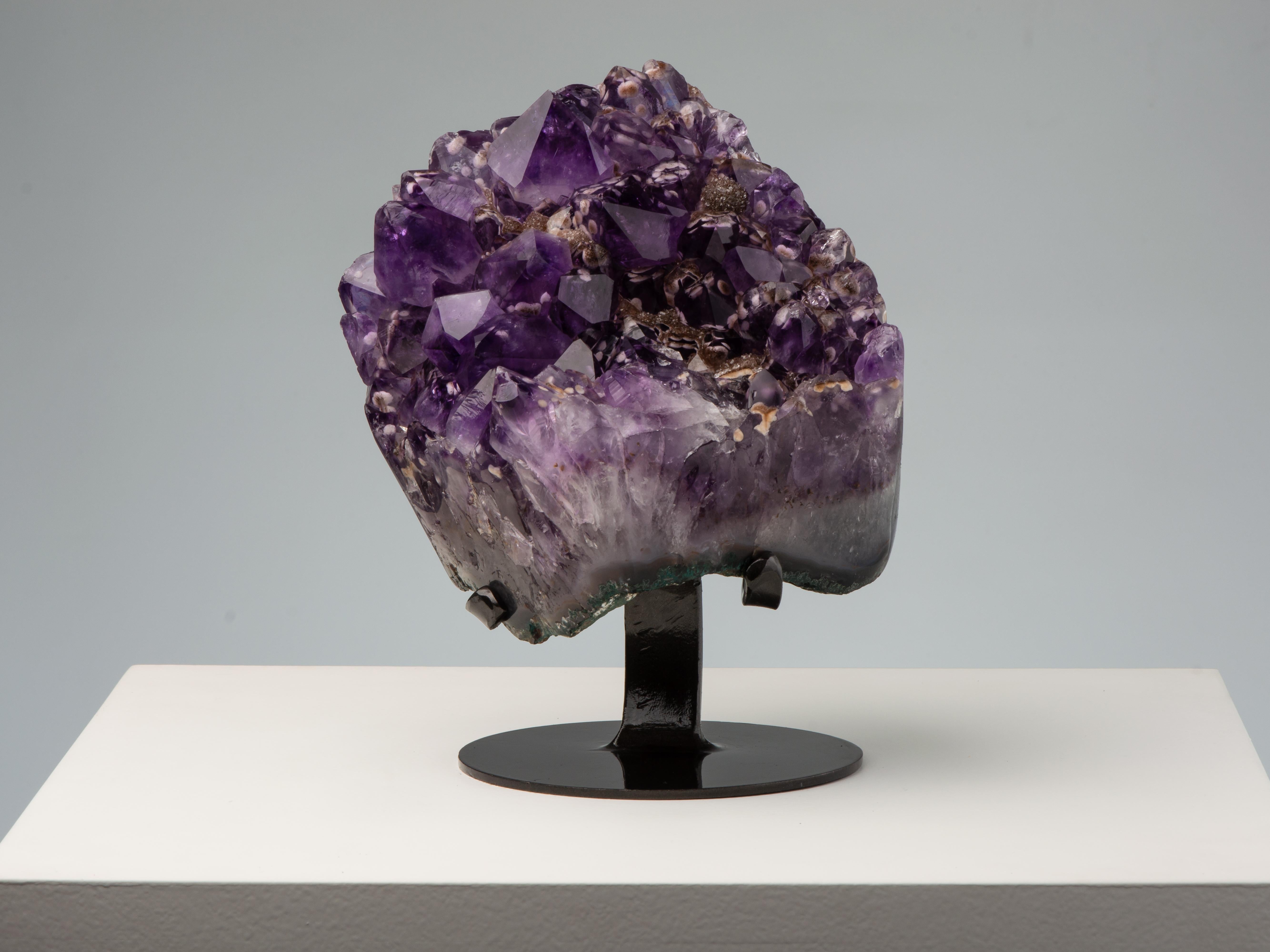 An unusual piece of high quality deep purple amethyst with large peaked crystals. Inside the amethyst multiple goethite crystals, resembling hearts and rosettes can be seen. Several of the crystals are over-coated in brown druze.

This piece was