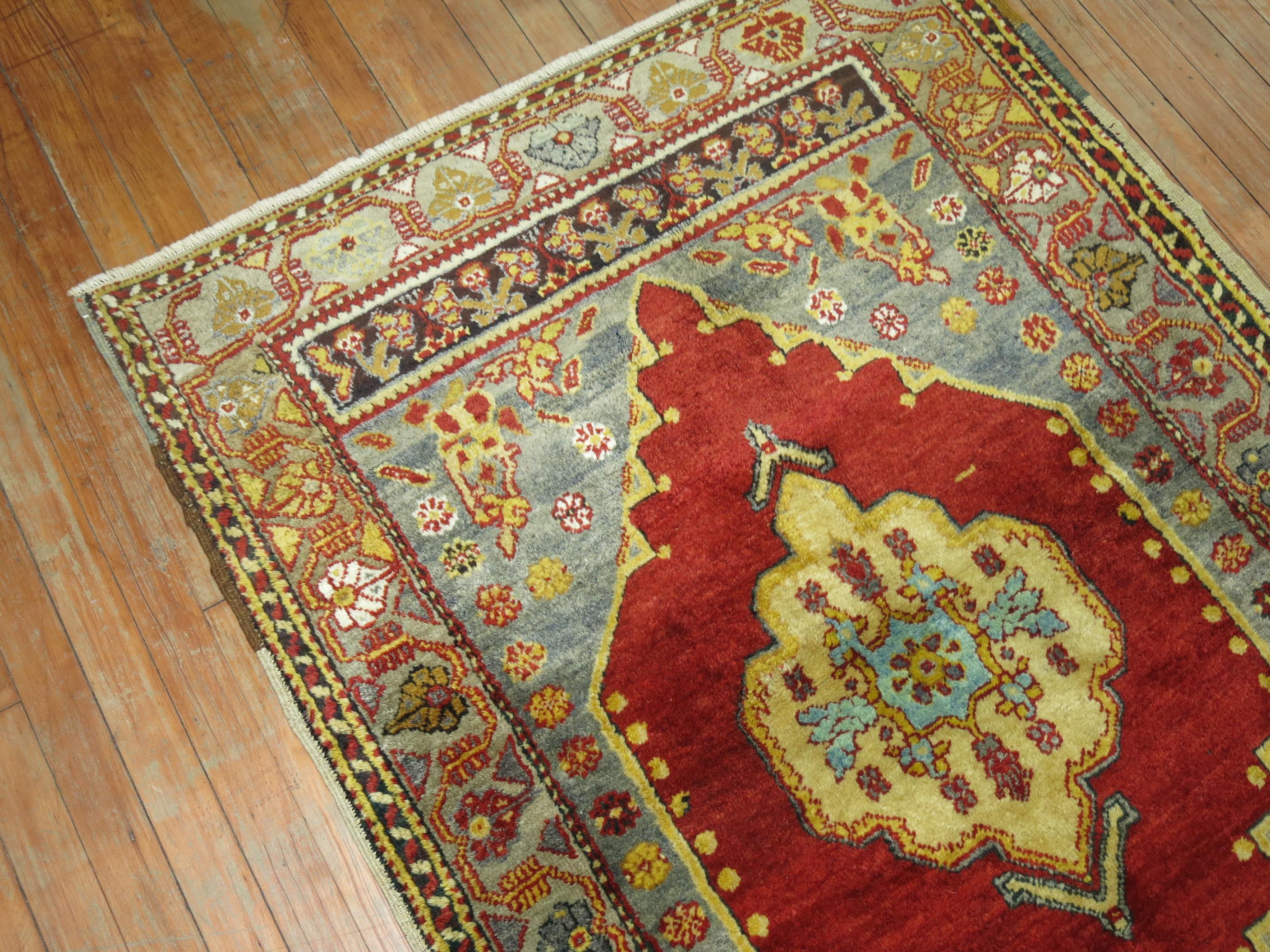 Un tapis Oushak turc ancien de taille dispersée, avec un champ rouge profond et des accents bleu ciel parsemés.