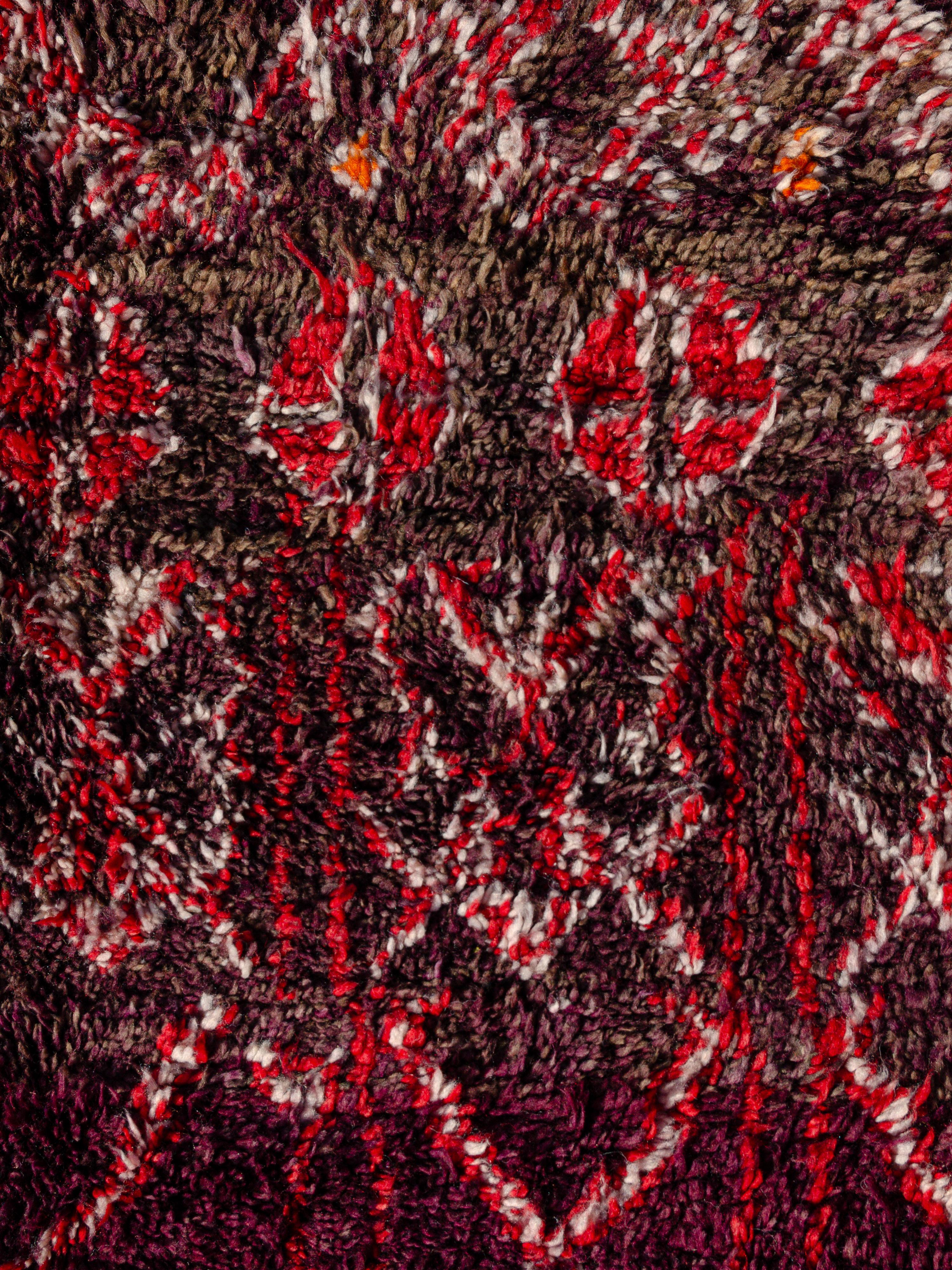 This vintage Moroccan Beni M‘Guild carpet features a female lozenge network that shifts in scale and structure in bands across the field. The motifs appear to grow and take on agricultural references as they morph. The masculine palette of plum,