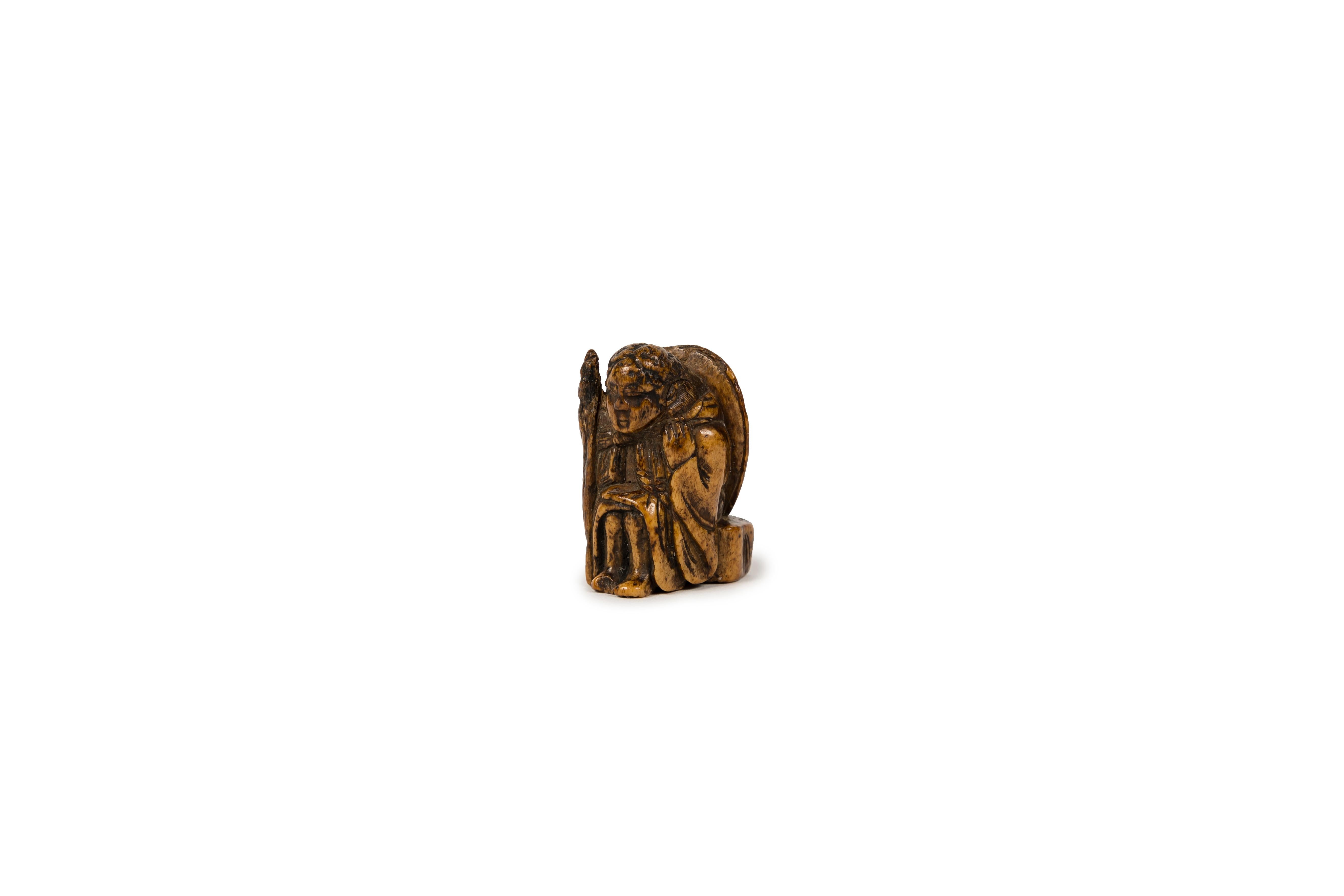Deer antler netsuke showing a man sitting on a chair with his back in the shape of a tortoise shell. His right arm is raised. 
In Japan, tortoise is a symbol of luck and longevity, it is thought to be a creature of good omen supposed to bring 10 000