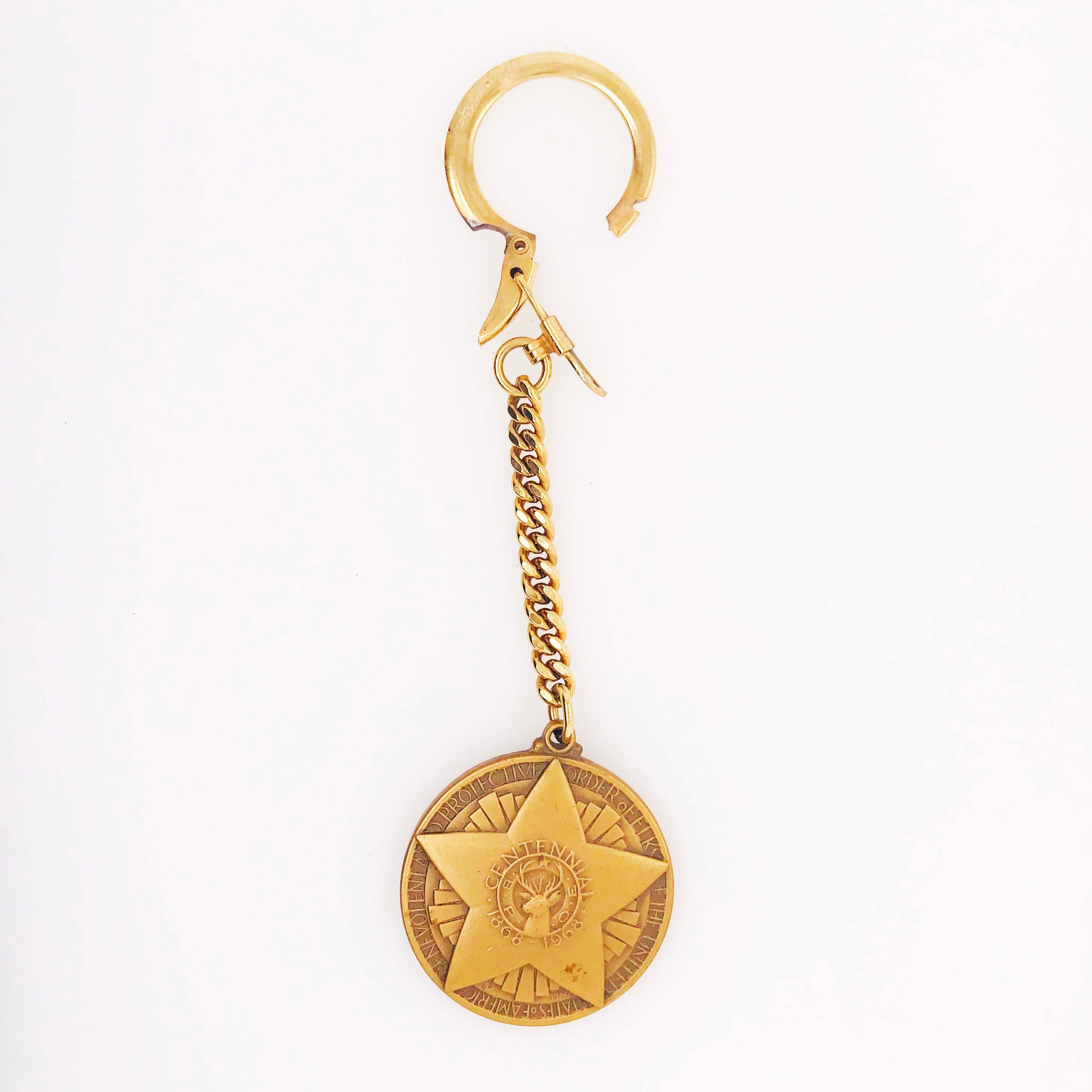 Gold Coin Keychain with Star and Deer accents! This incredible keychain is a unique design with a big star that has a profile of a glorious deer on the front. On the back of the keychain there is are deer antlers framed by a floral/vine seal design.