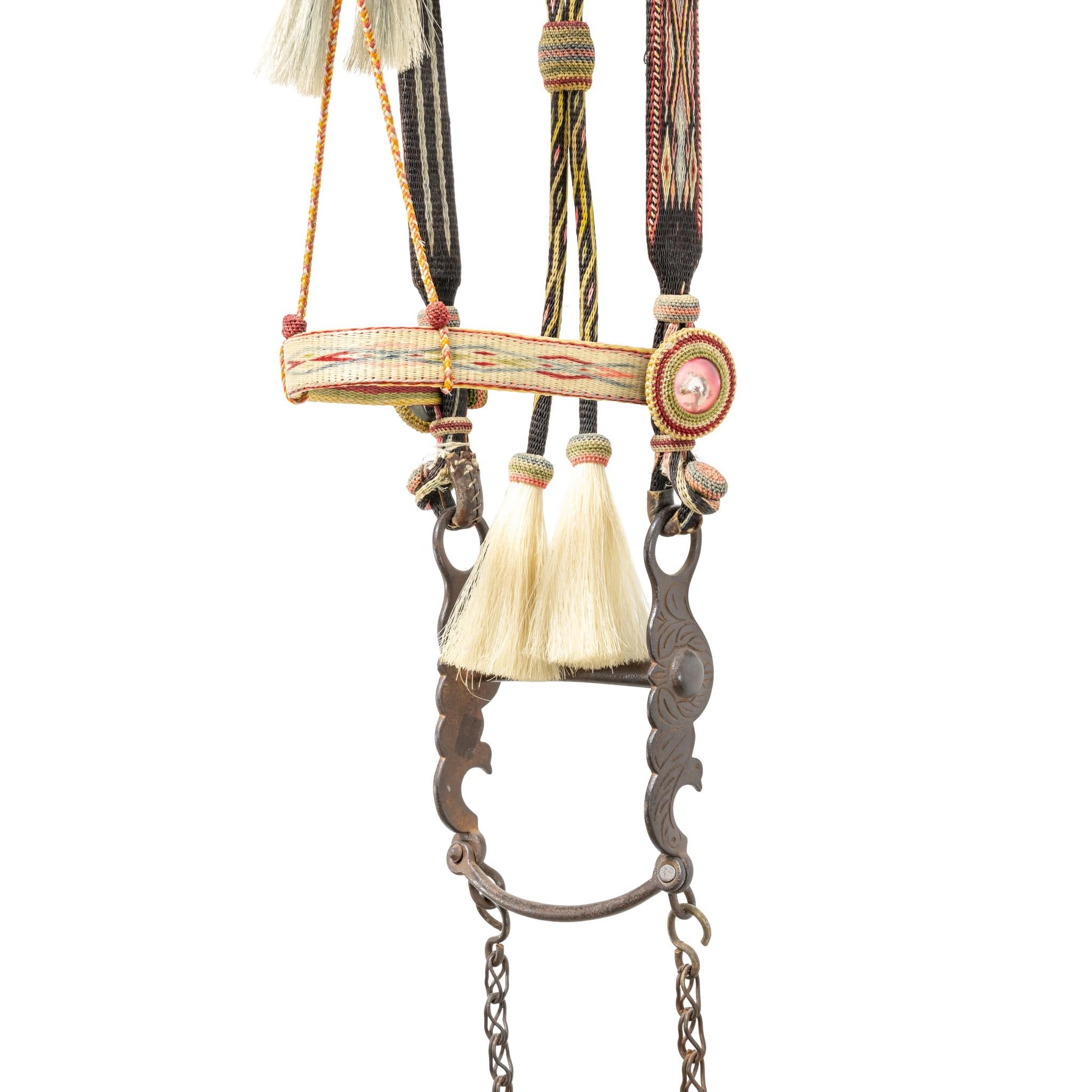 Deer Lodge Prison horsehair bridle. Cheekbands matching reins. Flat nose, brow, cheek, and headbands. Headbands attached with kangaroo leather and celluloid ring. Six foot black reins having American flags. Vintage Buermann bird bit. A used piece,