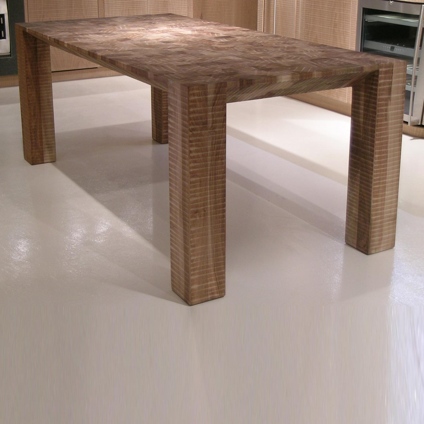 The solid Italian walnut wood of this elegant table is hand carved with gouge and plane. The result is a minimalist object made of three lines that evoke both the density and the substance of the matter they are made of.