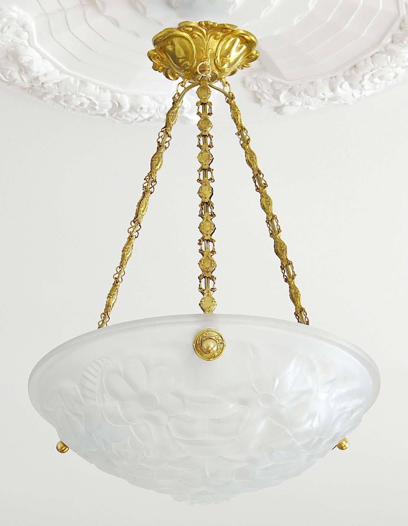 French Art Deco pair of pendant chandeliers by Degue (Compiegne), France, late 1920s. White frosted glass shades with an Art Deco stylized floral pattern. Stamped brass frames. Measures: Height 19.3
