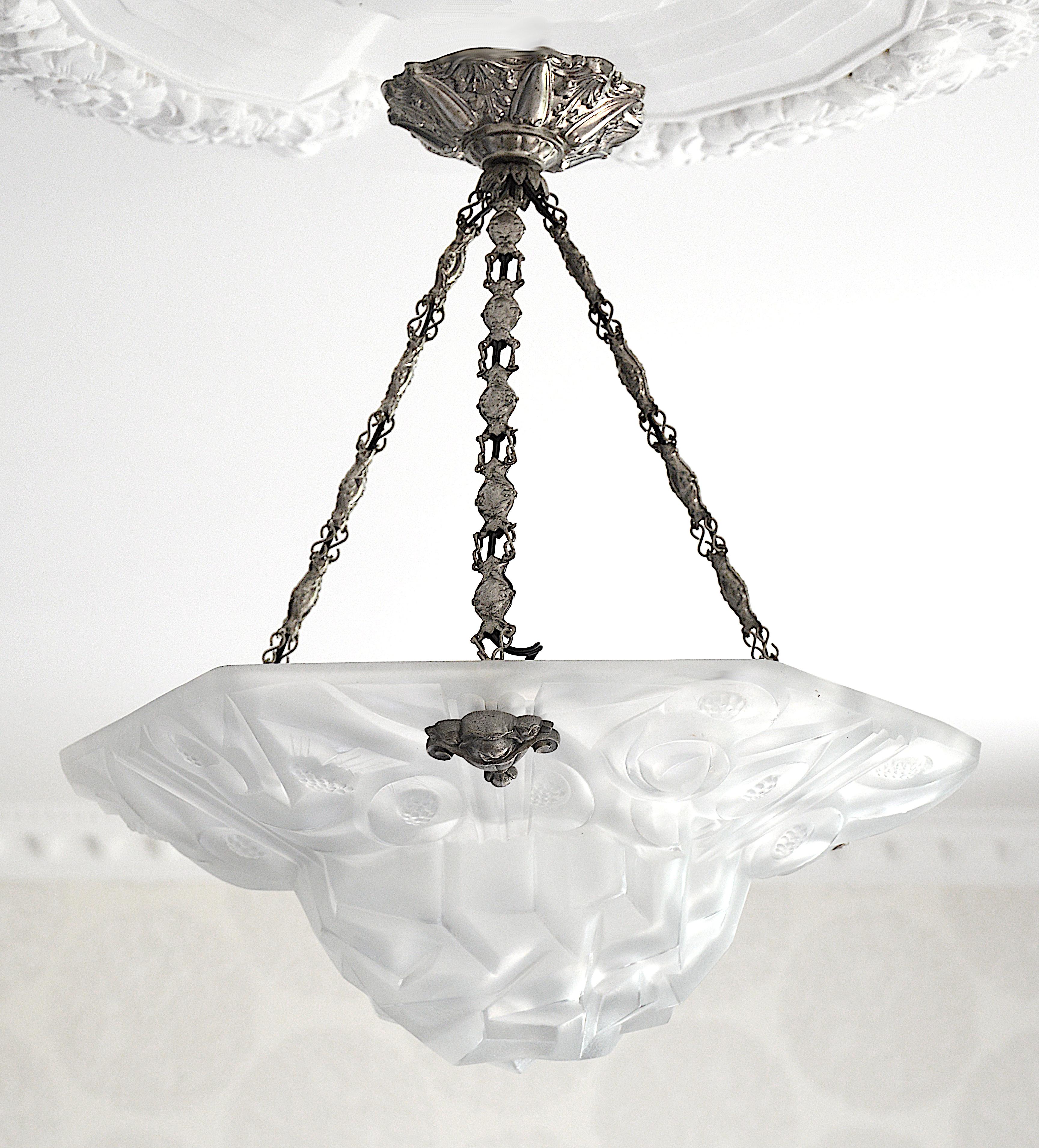Thick French Art Deco pendant chandelier by Edouard Cazaux at DEGUE's, France, 1928-1930. Thick white frosted glass shade with a stylized floral pattern with sharpen edges typical of the Cazaux's work. The silver plate stamped brass frame shows a