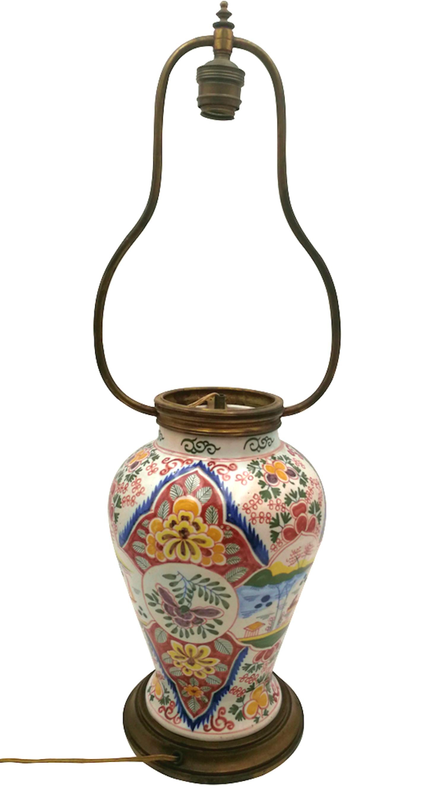A table lamp mounted on a hand-painted early 20th-century Delft vase, decorated with Chinese-
inspired floral motifs and a character in a boat. The wide colour palette is unusual for this type of
ceramic. The base and shade holder are in bronze or