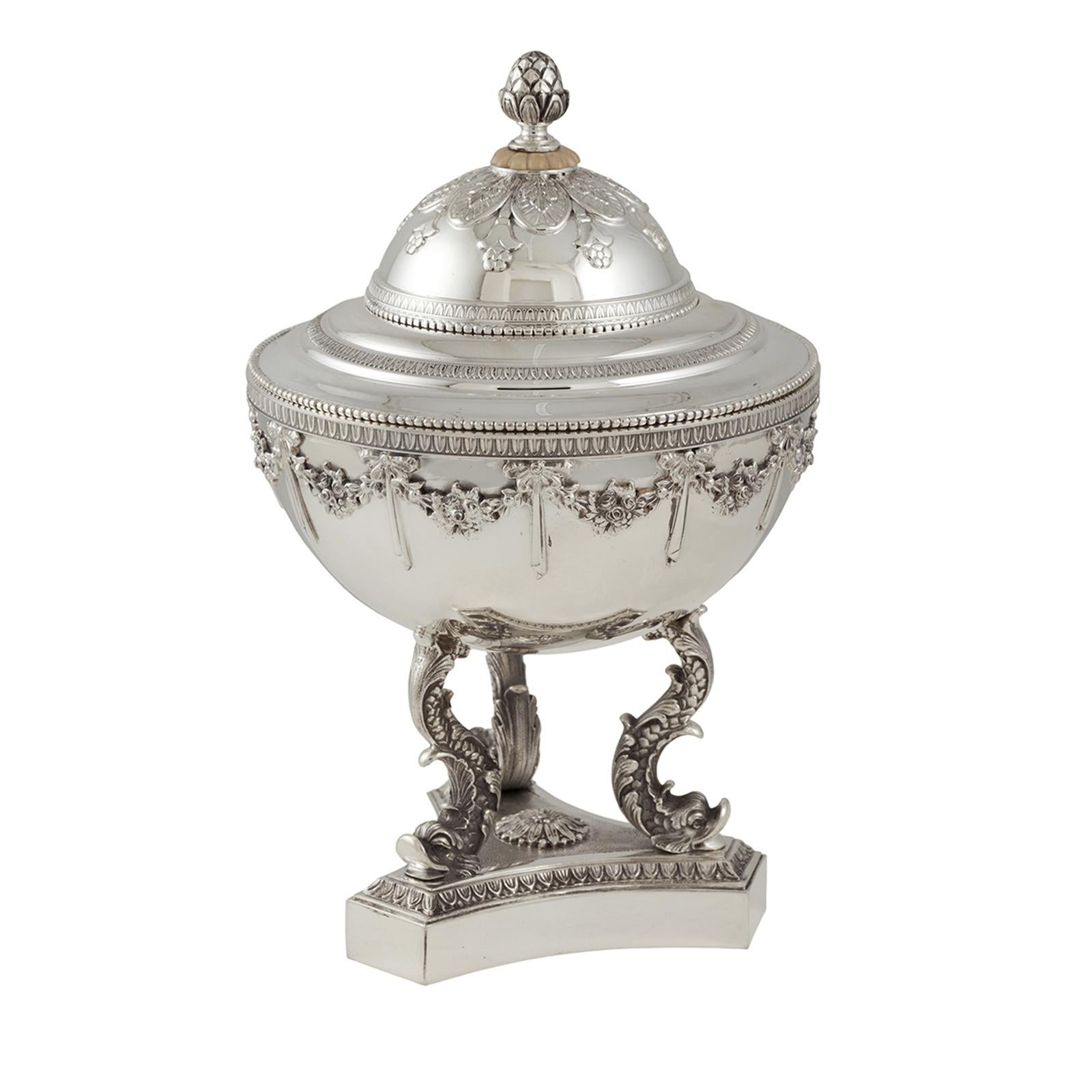 This magnificent bowl with lid and base is entirely made in silver and was specifically designed to store and serve caviar. Its Classic shape is adorned with Renaissance-inspired decorations, including three dolphins that connect the triangular base