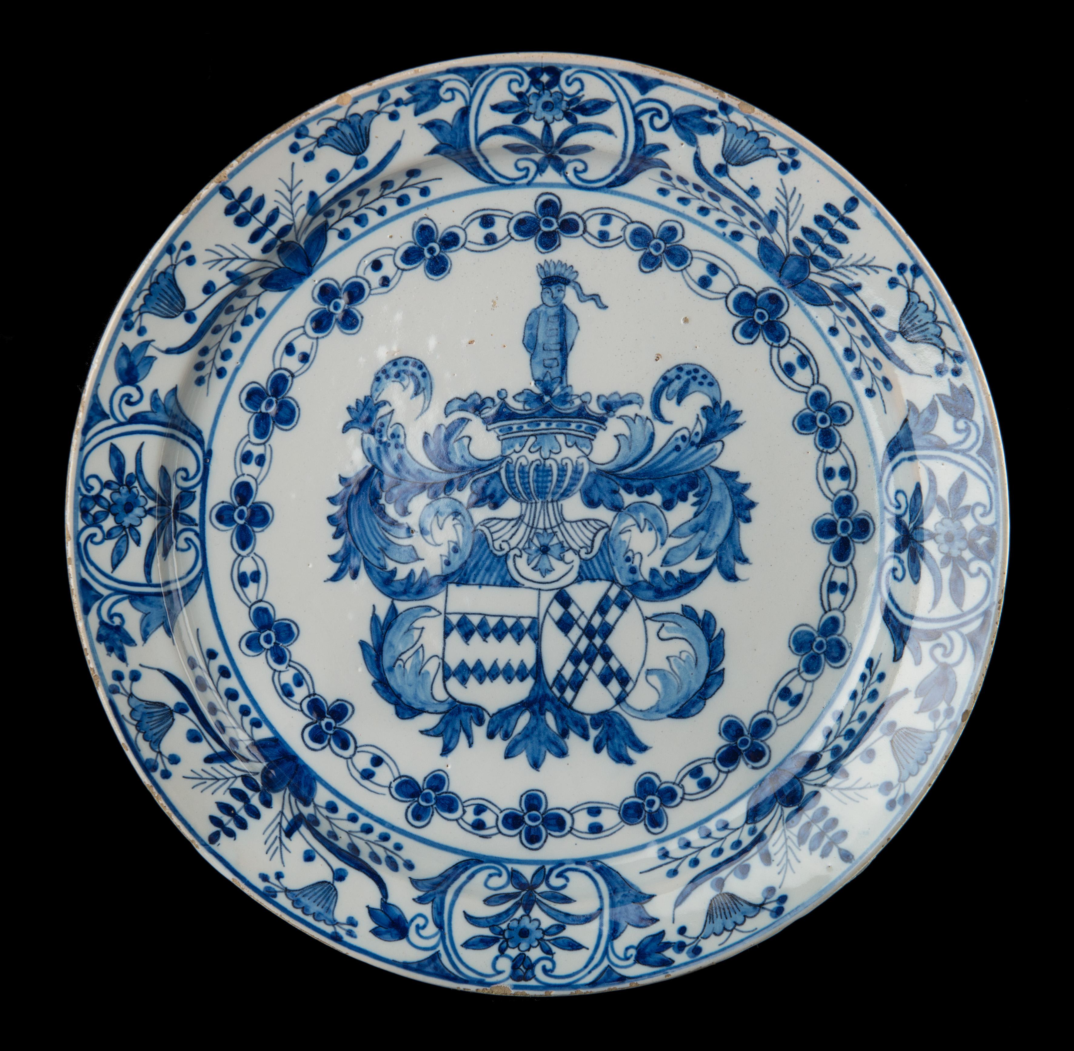Blau-weißes Wappenschild mit dem Wappen von Johan van der Does und Elisabeth van der Dussen. 
Delft, 1686-1701. Die griechische A-Töpferei. Zeichen: AK, Periode von Adrianus Kocx (1686-1701) 

Der blau-weiße Teller steht auf einem Fußrand und ist