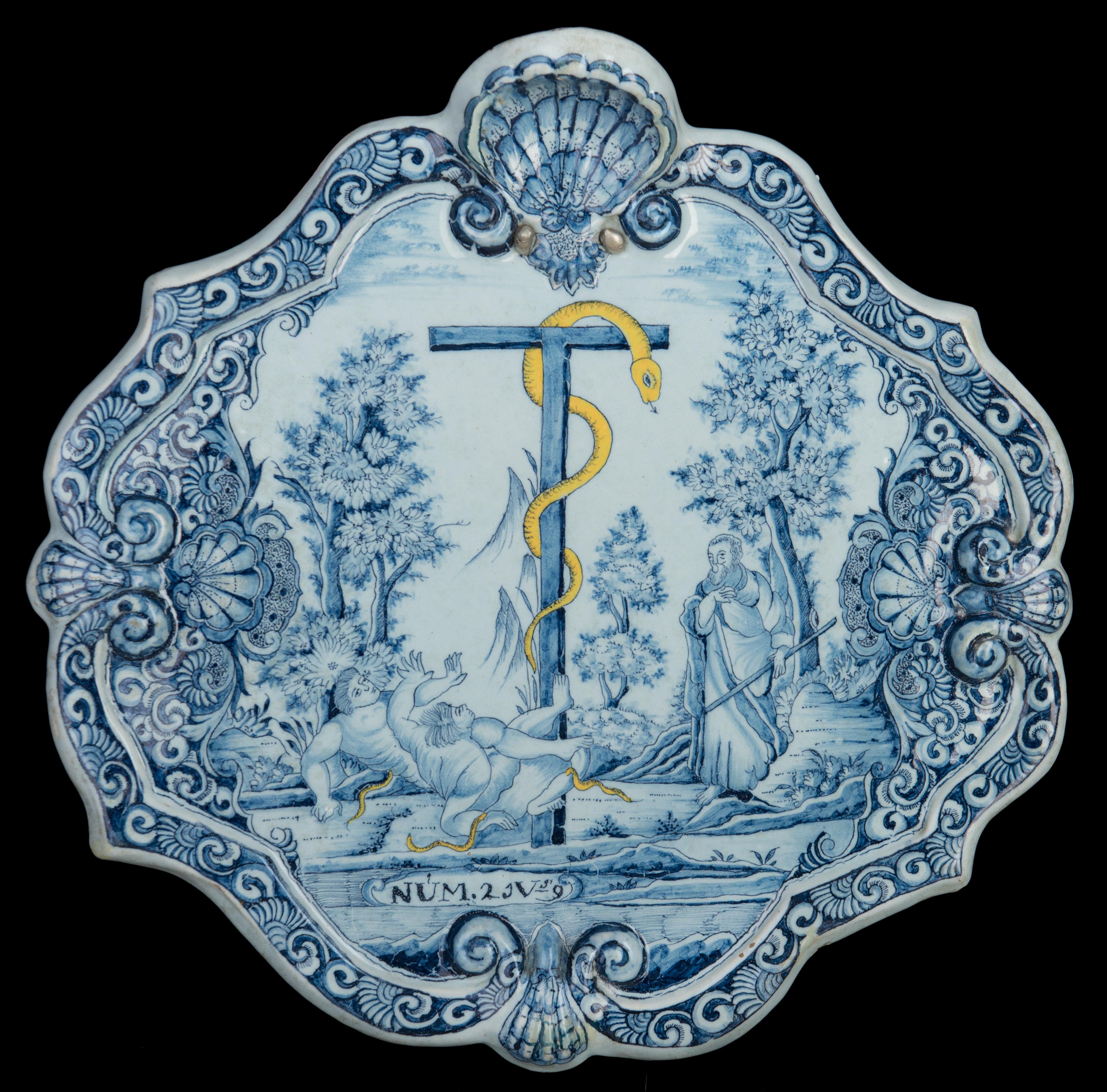 Biblical plaque with Moses and the bronze snake in blue and white and yellow. Delft, 1740-1760.

The lozenge-shaped plaque has a molded and raised rim made up of scalloped ribbons alternating with shells. The plaque is painted with the biblical