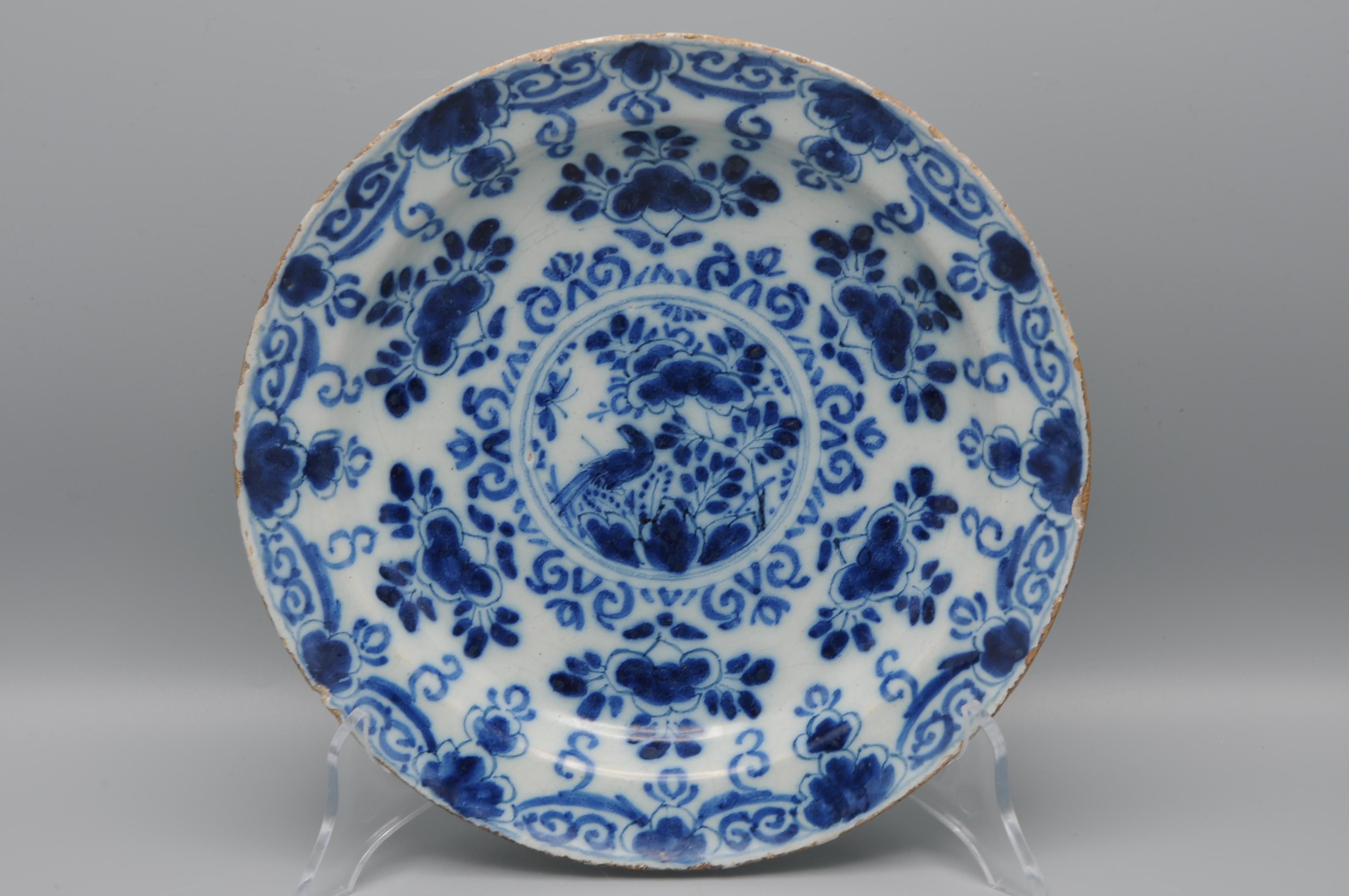 Assiette en faïence de Delft à décor de chinoiseries bleues d'un médaillon central représentant un oiseau sur une branche fleurie. Les bordures sont ornées de feuillages et de rinceaux géométriques. 

Première moitié du XVIIIe siècle. 

Très bon