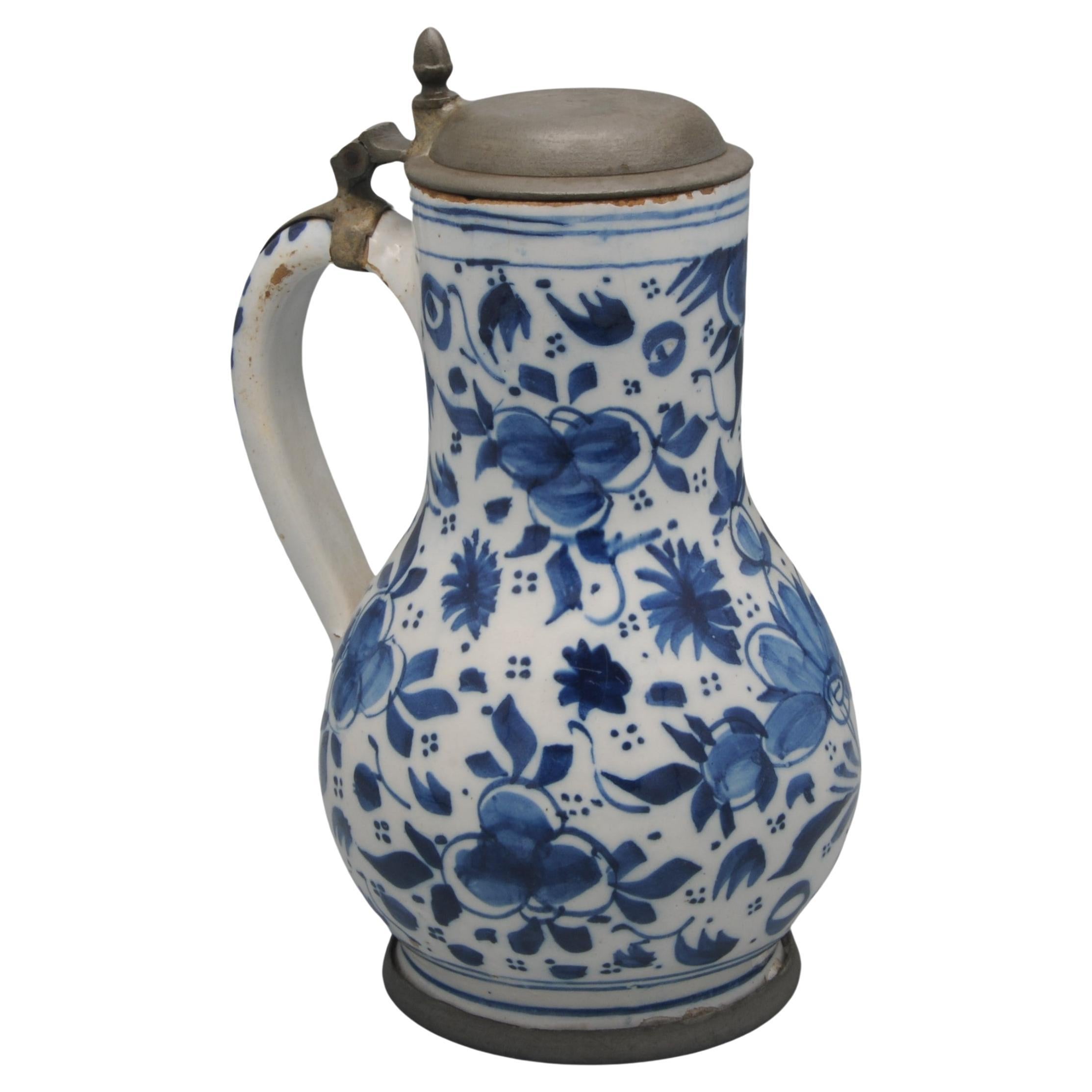 Dutch Delftware beer jug with bright blue decoration of flower buds and foliage springs. 
With later pewter lid and foot rim.