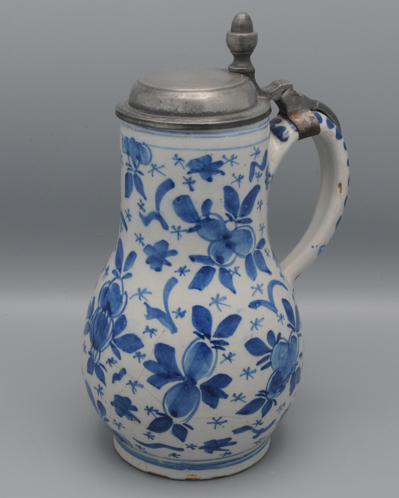 Jarra de cerveza holandesa de Delftware del siglo XVIII con decoración azul brillante de capullos de flores y brotes de follaje. 
Tapa de peltre posiblemente de la época.
