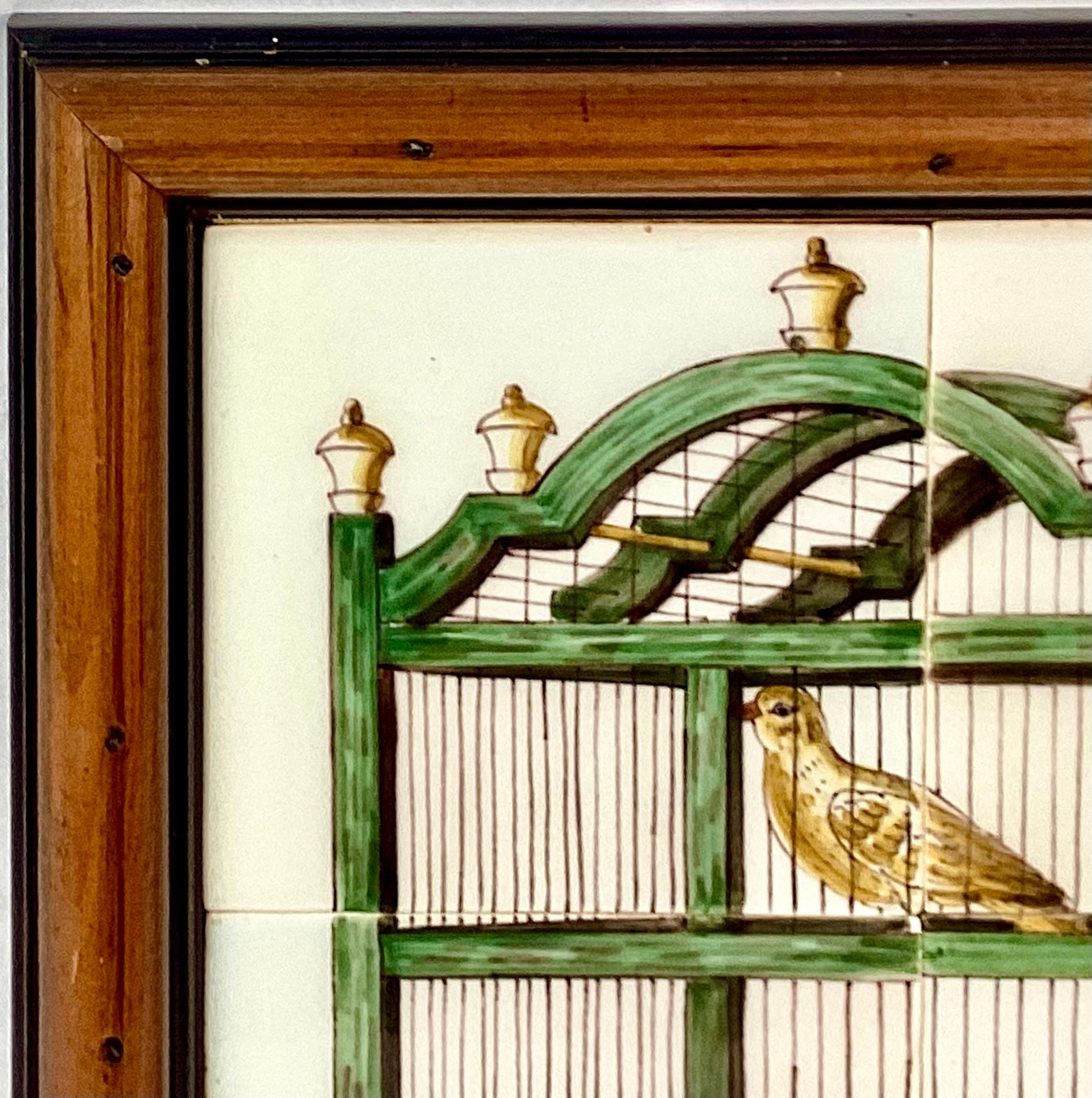 Delft 18th Century style tiles featuring a bird in a cage. Mural has four approximately 5 x 5 tiles. These are painted with a green bird cage and yellow bird perched inside with yellow finials and a blue water bowl mounted in a custom wood frame. 