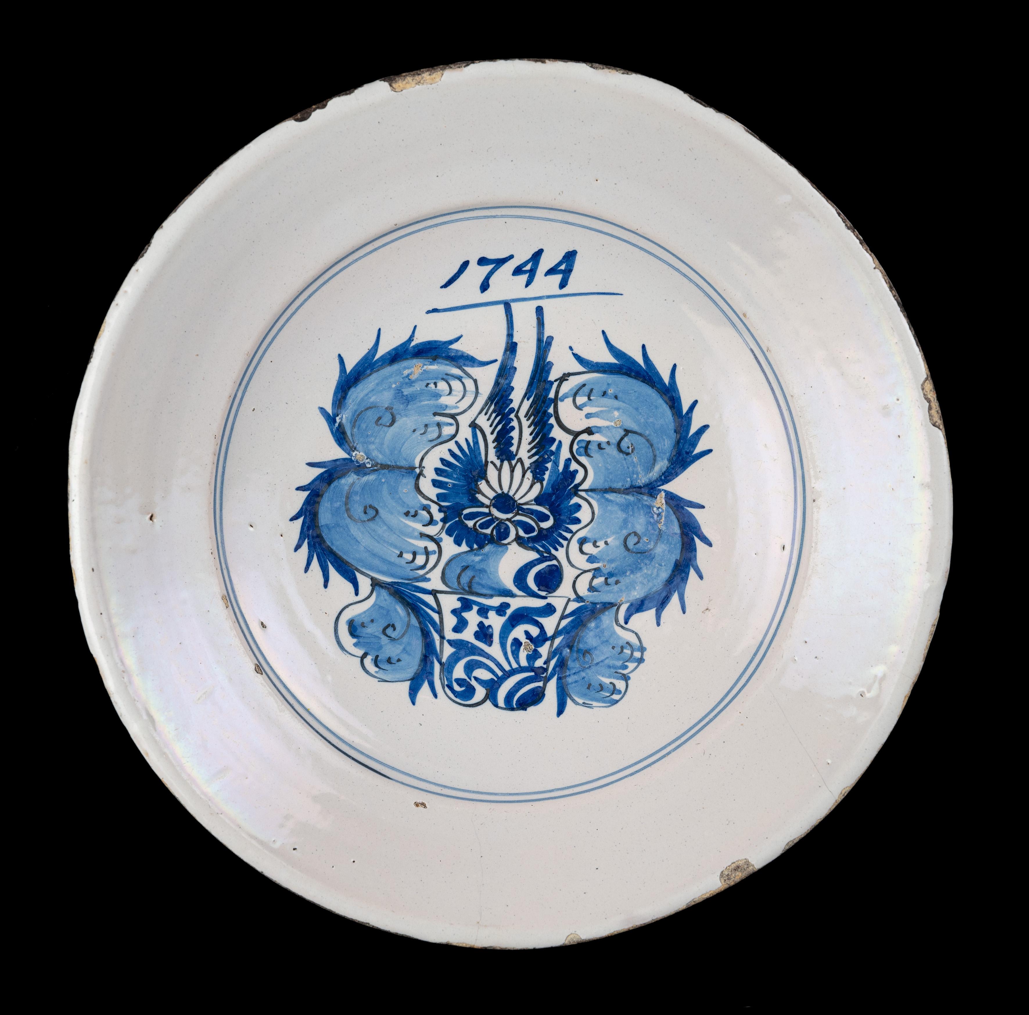 Blue and white armorial dish. Harlingen, dated 1744

The dish has a wide raised flange and is painted in blue with a coat of arms and the year 1744. The depiction is framed within a double circle, the flange is unpainted. Three stilt marks, which