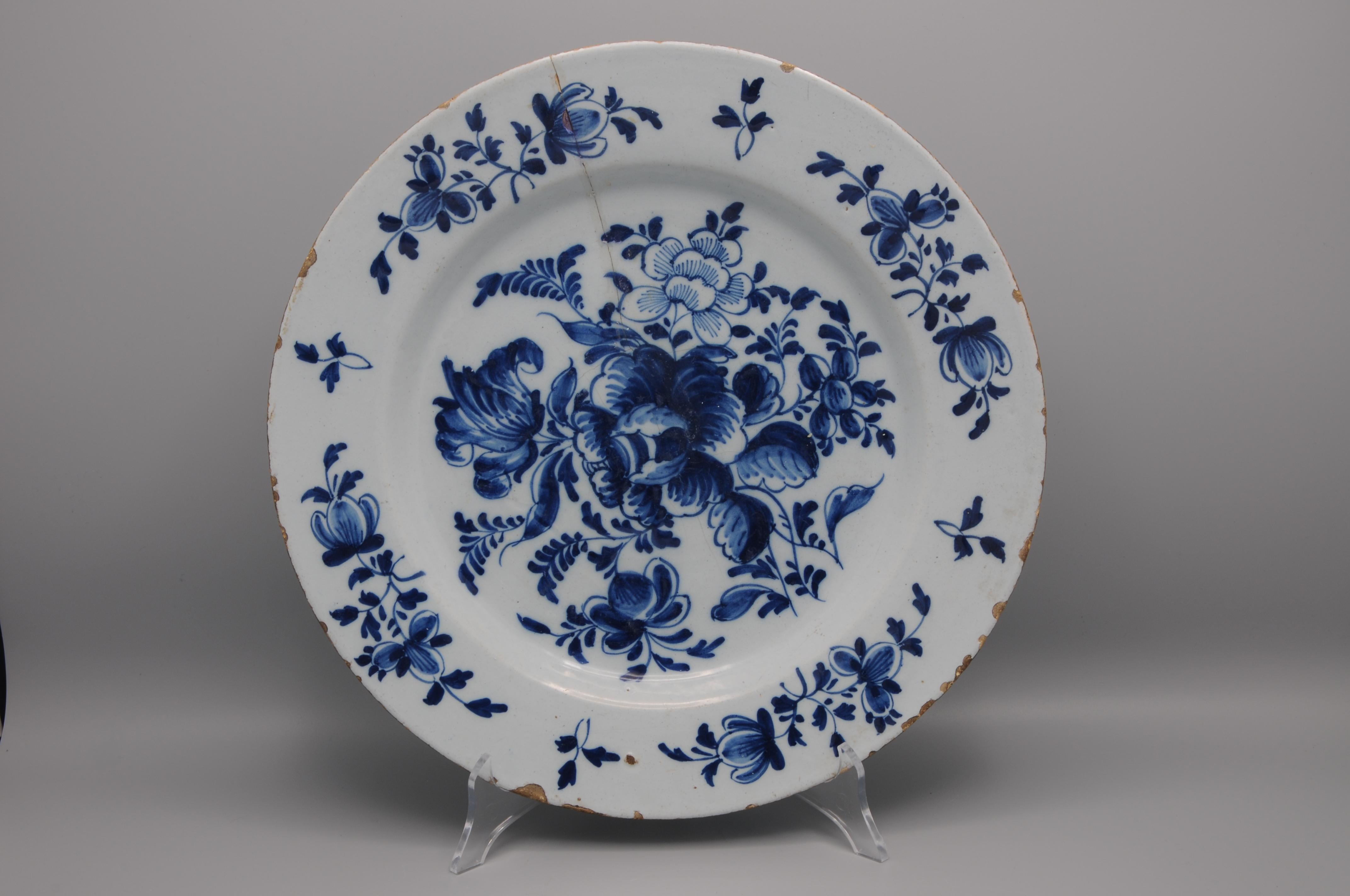 Chargeur Delft hollandais, 18e siècle, en faïence étamée peinte en bleu de cobalt. La composition centrale montre un grand bouquet floral bien équilibré avec une bordure de fleurs plus petites, un motif caractéristique de Delft influencé par la