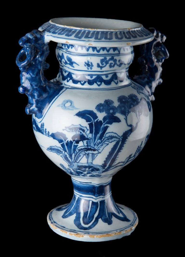 Blue and white chinoiserie altar vase. Delft, circa 1685
The ovoid altar vase stands on a high-waisted foot. The flaring cylindrical neck ends in an outward sloping mouth rim. The two blue coloured lion-shaped handles have suspending rings in their